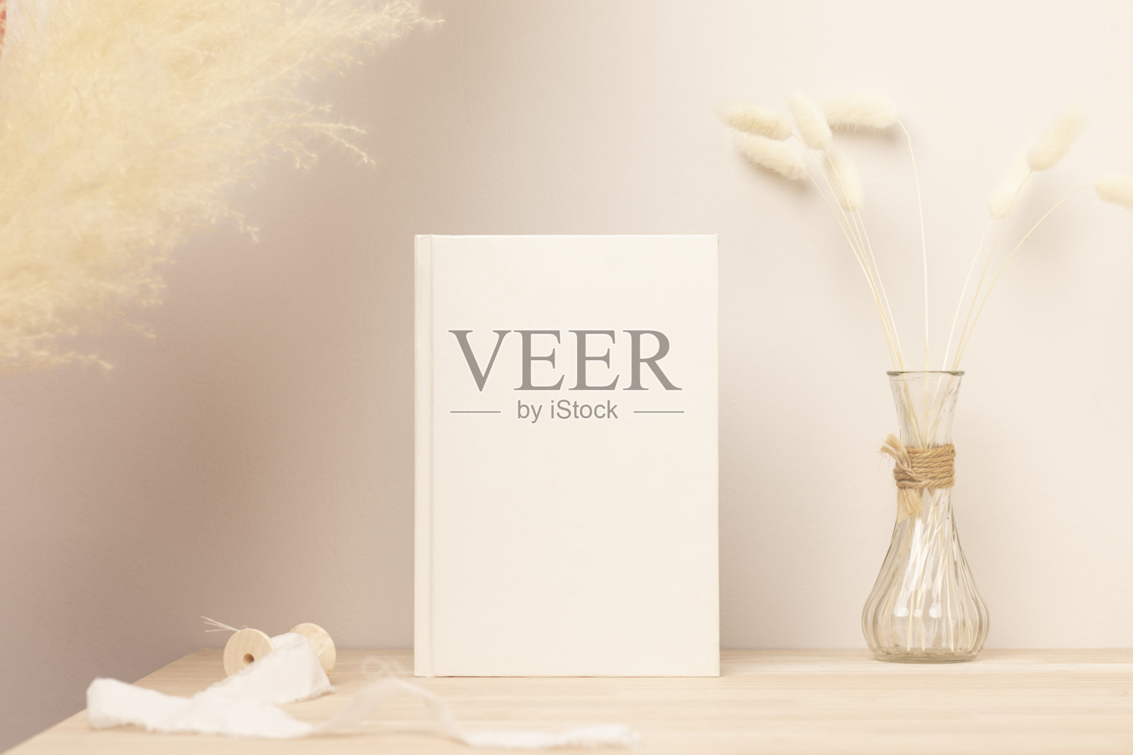 空白纸卡片，贺卡模拟。装饰与干燥的兔子尾巴和潘巴斯草，前视图，美丽的兔子尾巴草花瓶在木桌和米色水泥墙背景照片摄影图片