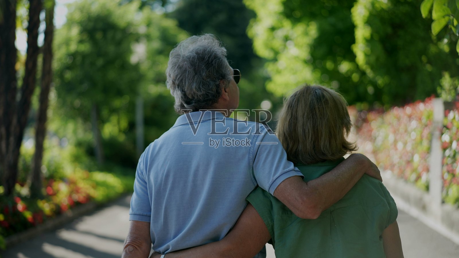 浪漫的老丈夫挽着妻子，老两口一起走在绿色的小路上照片摄影图片