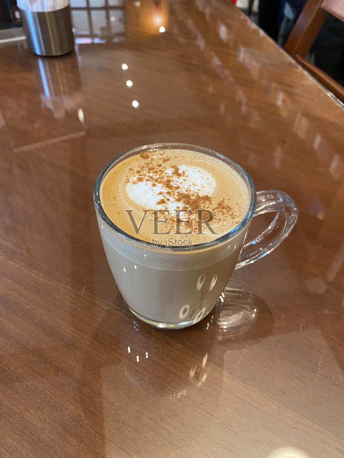 在当地的咖啡店，用杯子装南瓜拿铁，配上肉桂和肉豆蔻，手拿。照片摄影图片