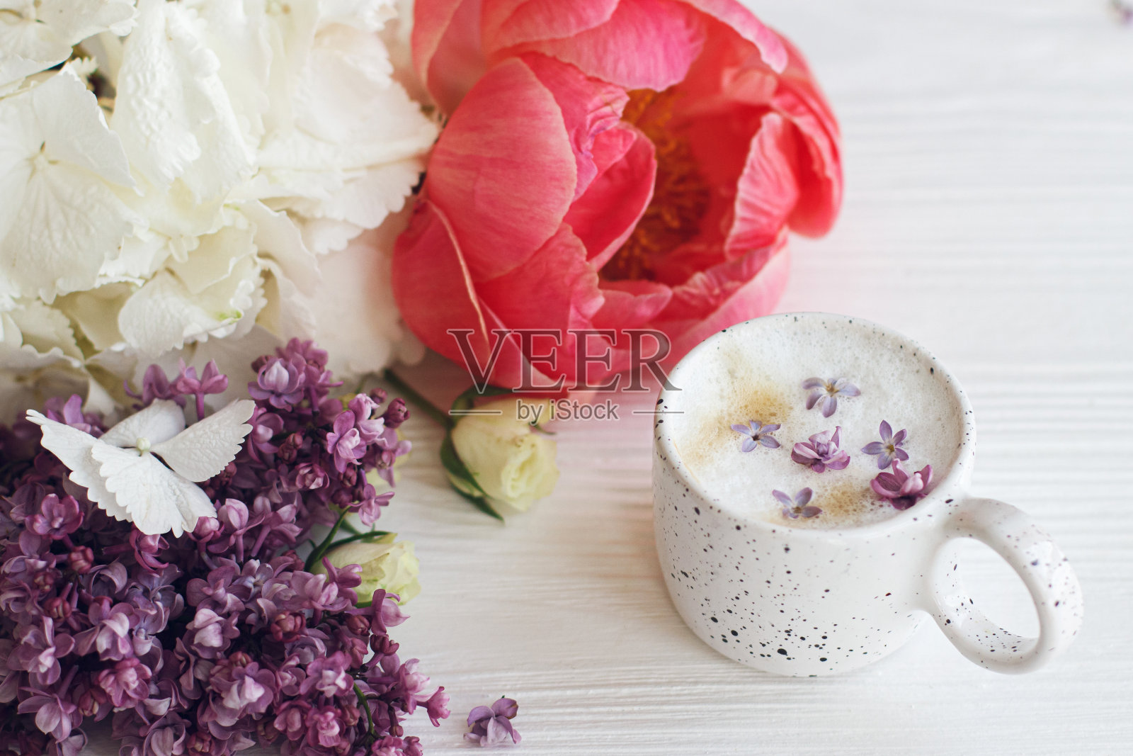 美丽的牡丹花、丁香花、玫瑰花搭配时尚的咖啡杯。快乐的母亲节。早上好。美味的咖啡与丁香花瓣和时尚的花束在白色木制背景照片摄影图片