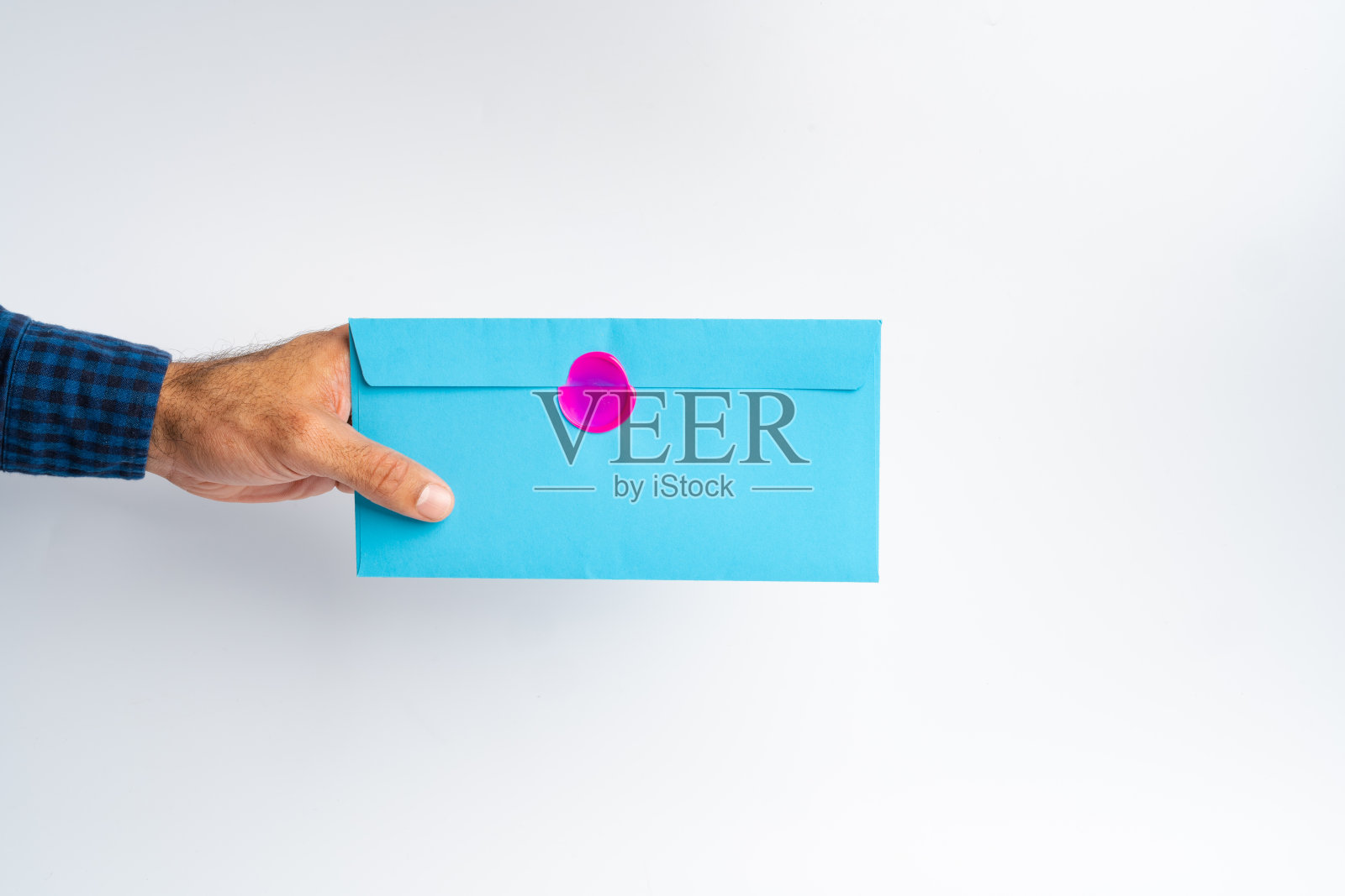 男性的手在白色表面上拿着封闭的信封照片摄影图片