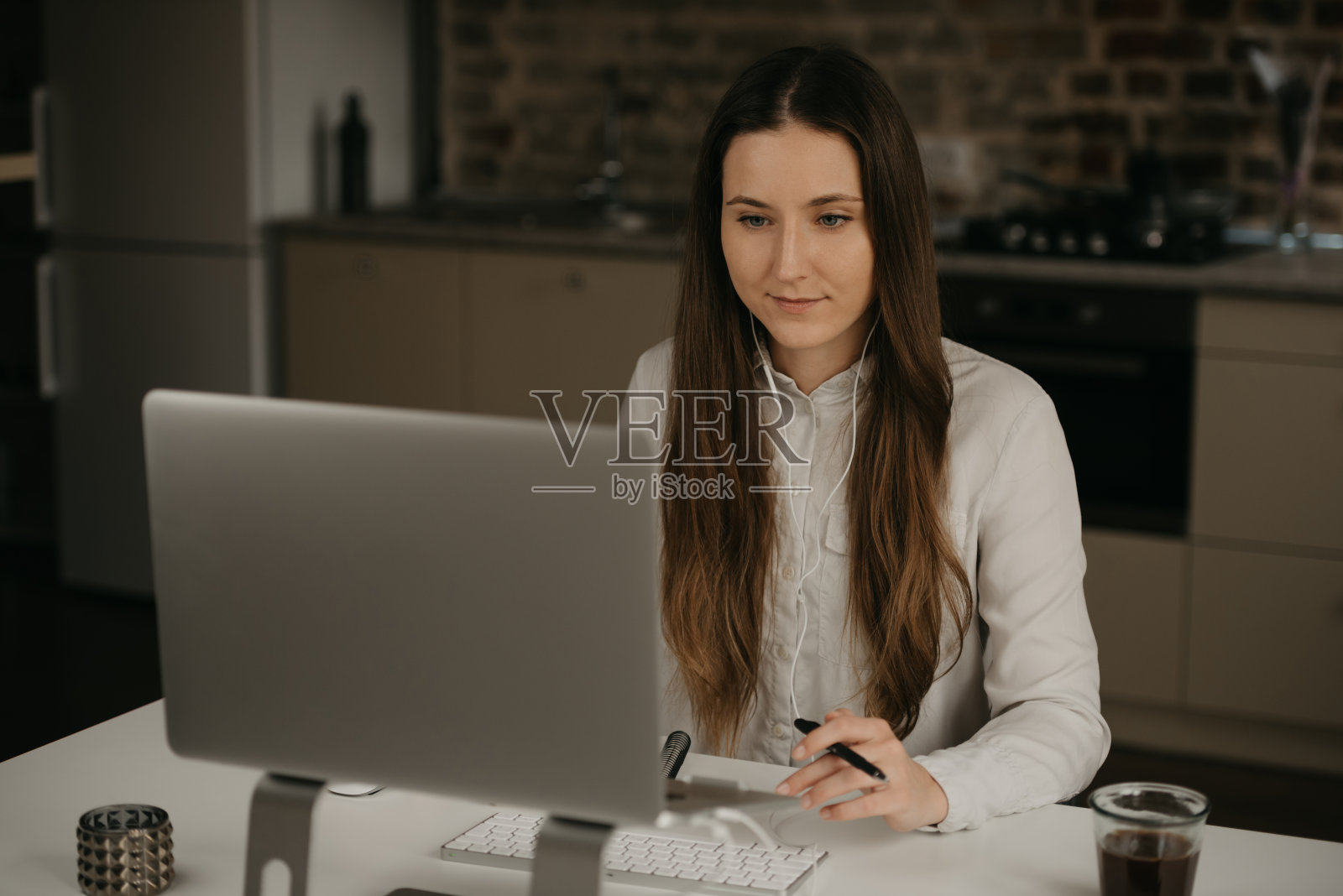 一个戴着耳机的白人妇女在家用她的笔记本电脑远程工作。照片摄影图片