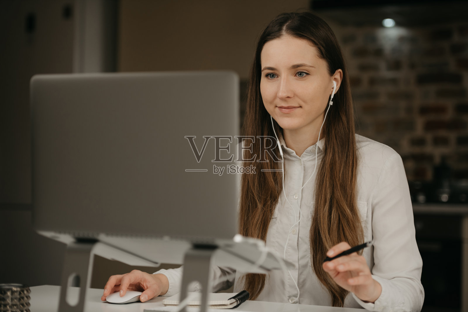 一个戴着耳机的白人妇女在家用她的笔记本电脑远程工作。照片摄影图片