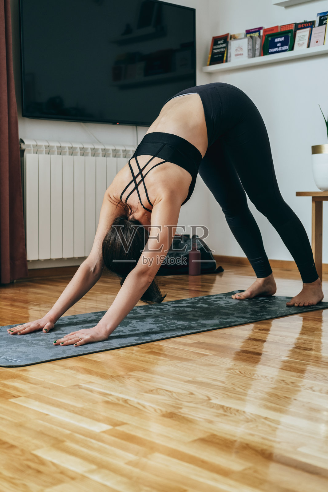 一个匿名的女人在早上练习瑜伽，做下犬式练习照片摄影图片