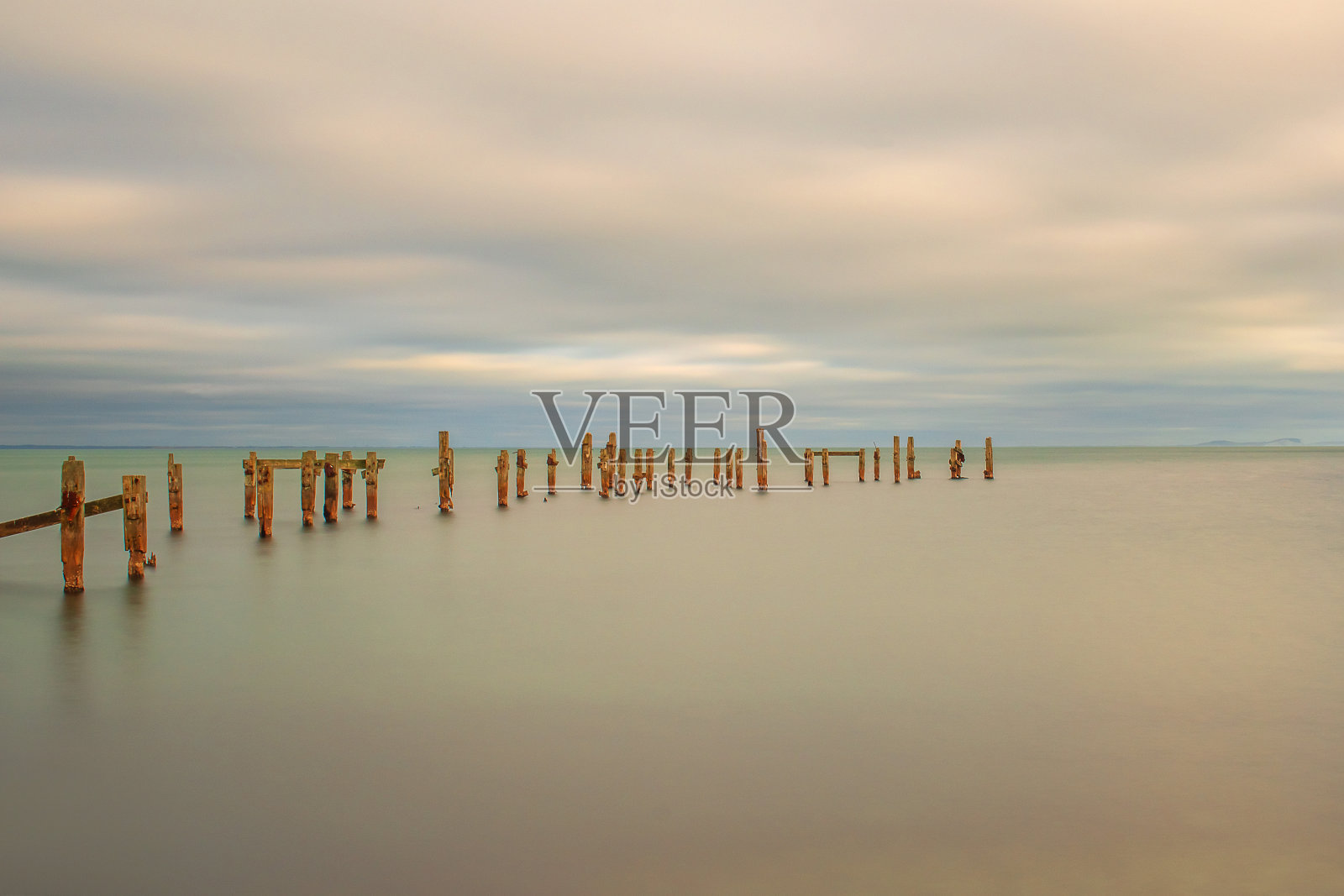 这是一张极简主义的图片，老天鹅码头的支柱伸出来，缓慢的快门上是粉红色的大海照片摄影图片