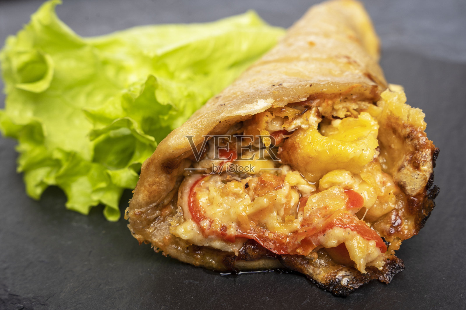 一款美味的蛋筒披萨，外皮酥脆，有融化的奶酪，新鲜的蔬菜和香料照片摄影图片