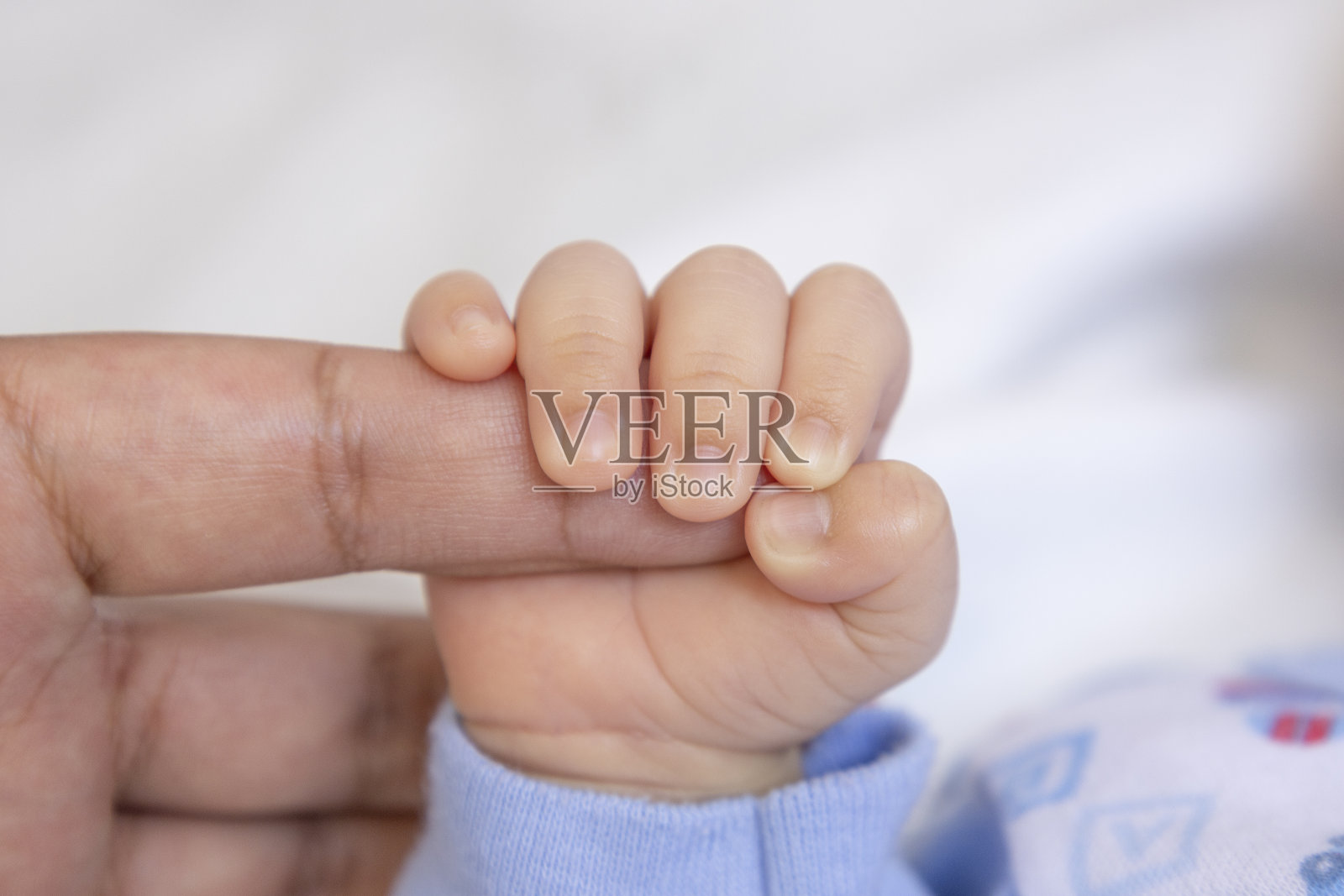 一个新生儿的手握着他父母的手指提供保护，新生命的纯真，爱的概念和照顾婴儿照片摄影图片