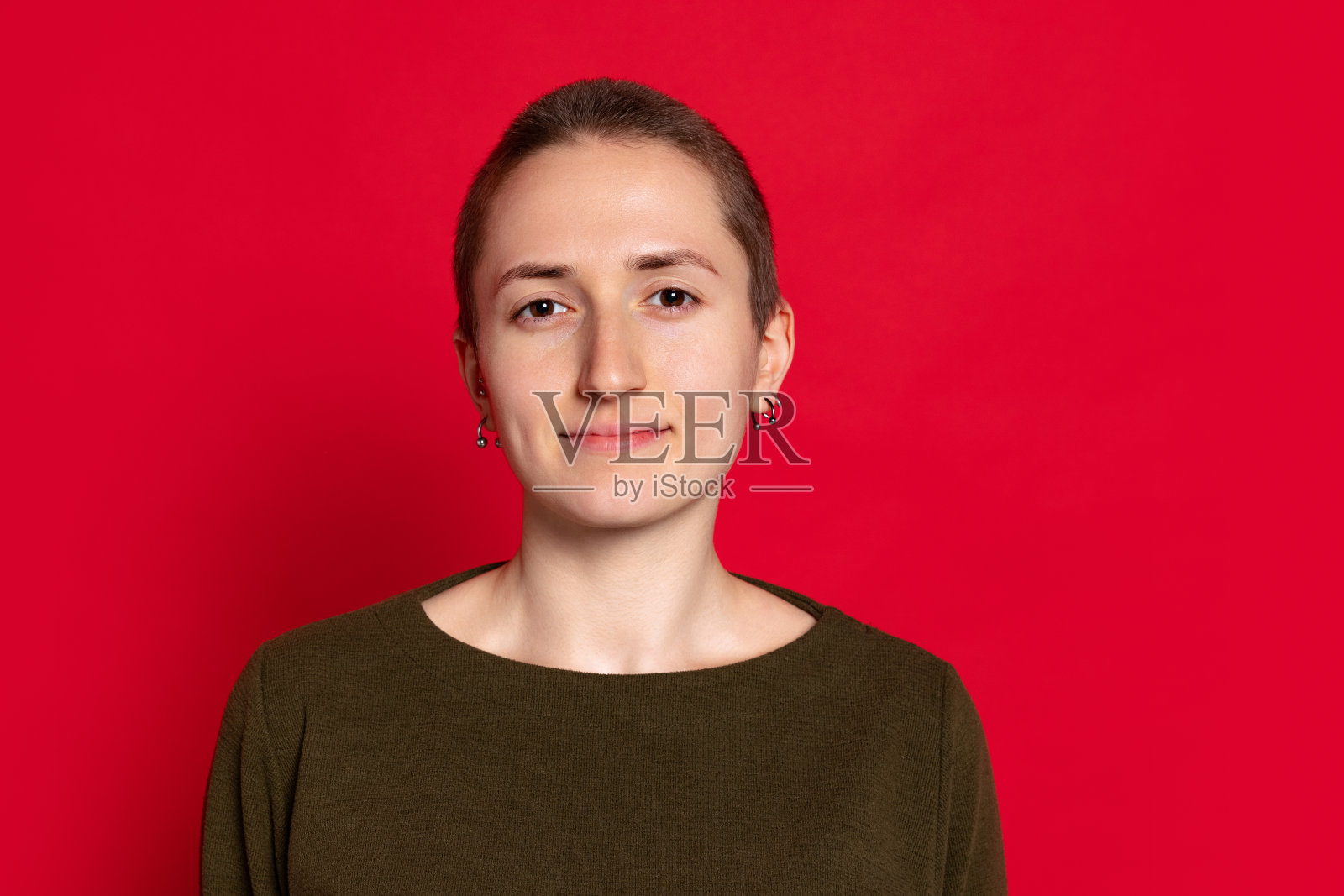 年轻微笑的女人的肖像，学生短头发在黑色毛衣孤立在红色的背景。情感概念，学习，广告照片摄影图片