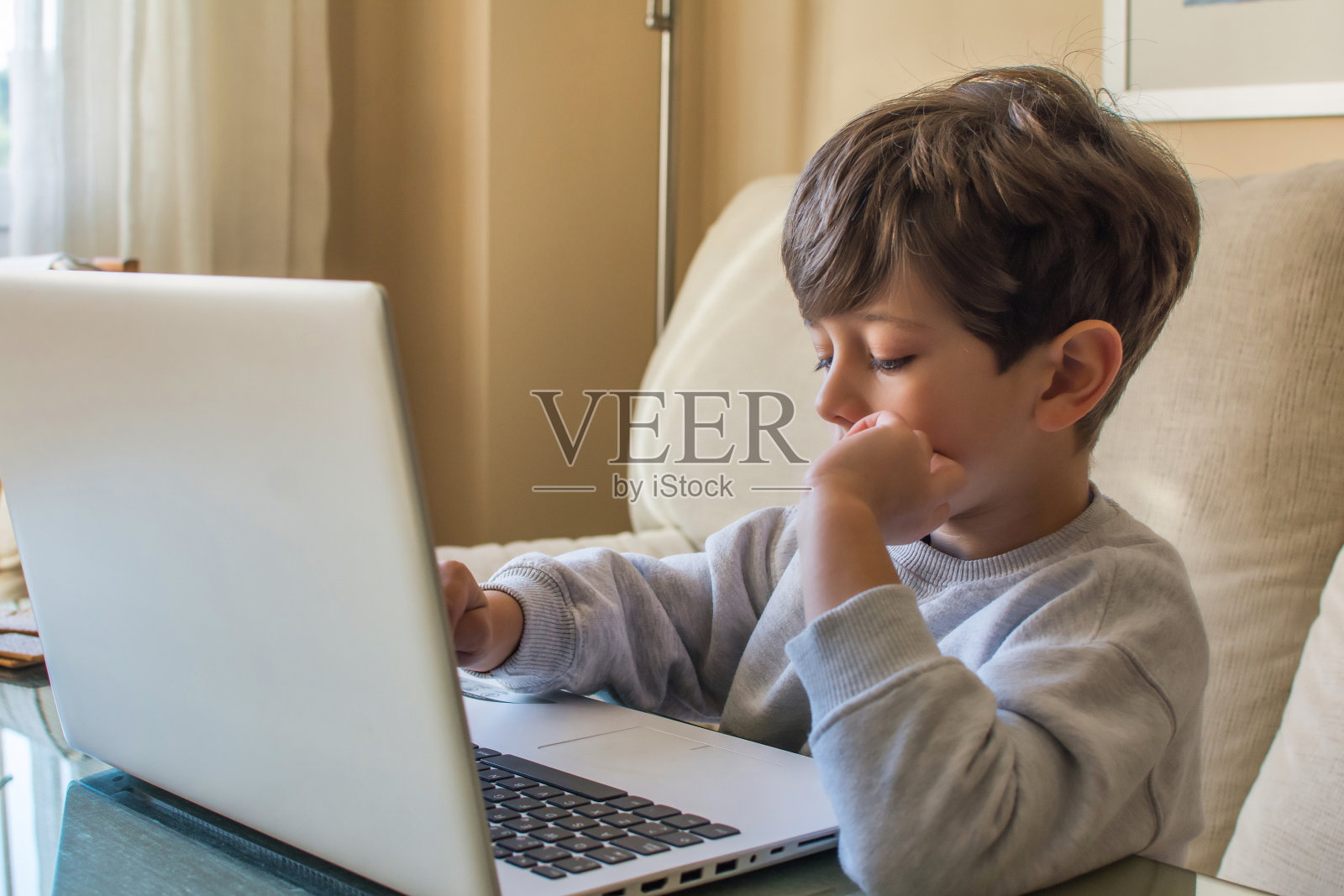 年轻的白人男孩使用笔记本电脑。照片摄影图片