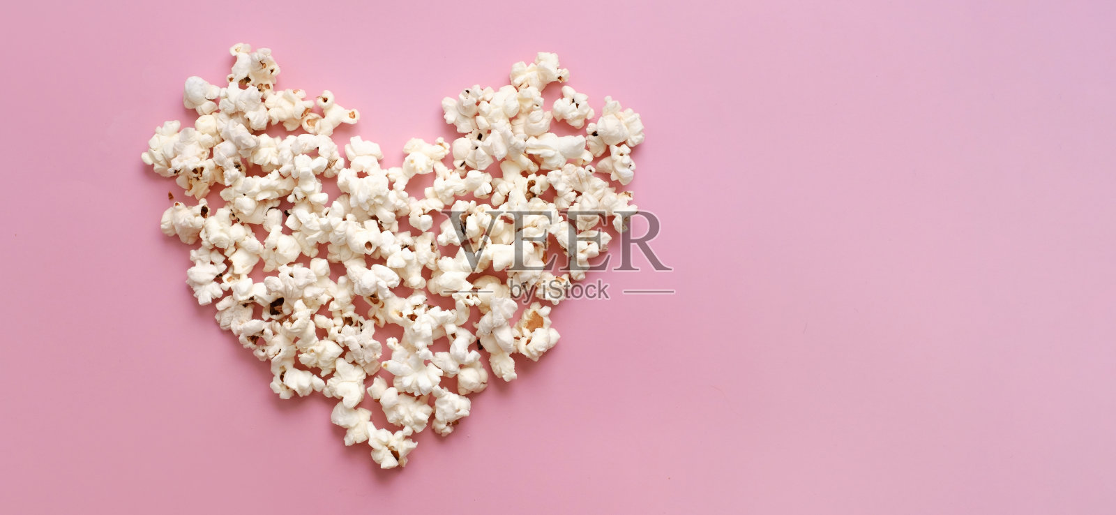 粉红背景上的爆米花心。情人节拷贝空间照片摄影图片