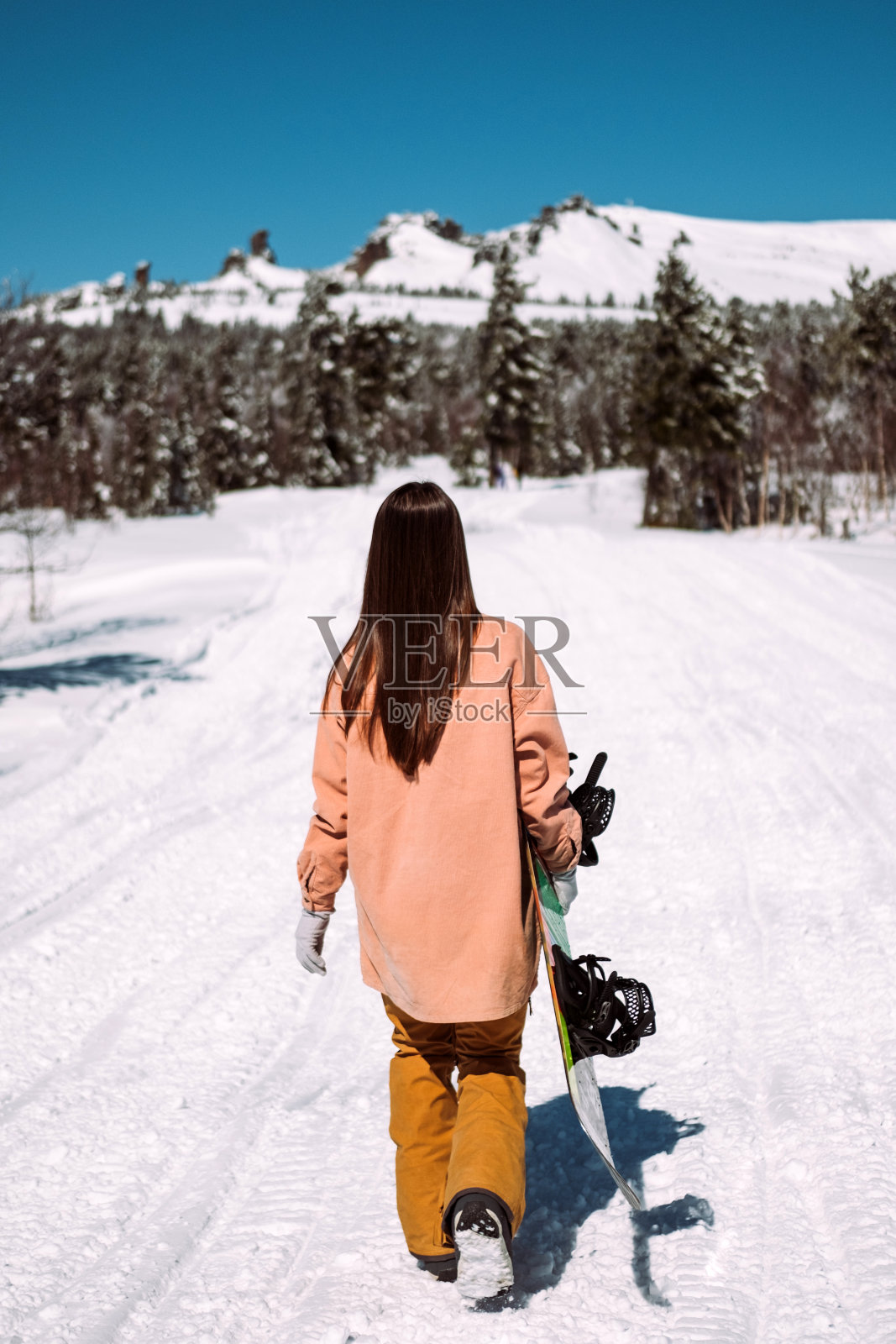 年轻的女孩滑雪板与一个滑雪板在自然的山在阳光明媚的天气照片摄影图片