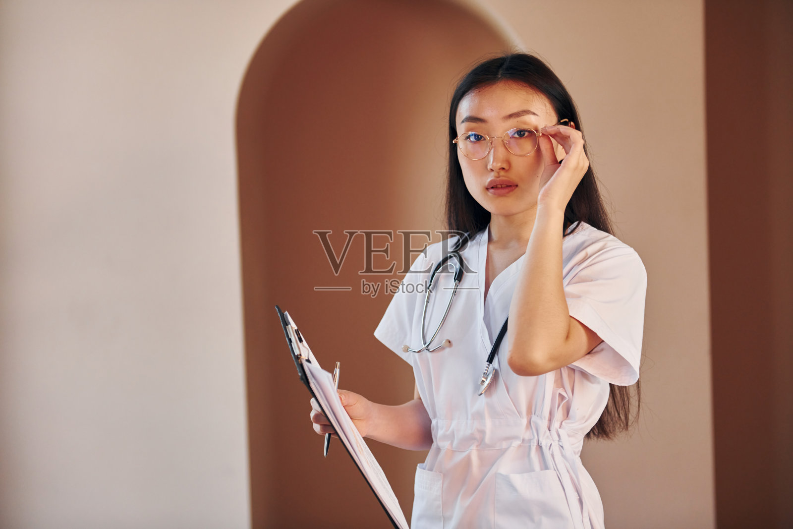 手里拿着笔记本。年轻严肃的亚洲妇女站在室内照片摄影图片