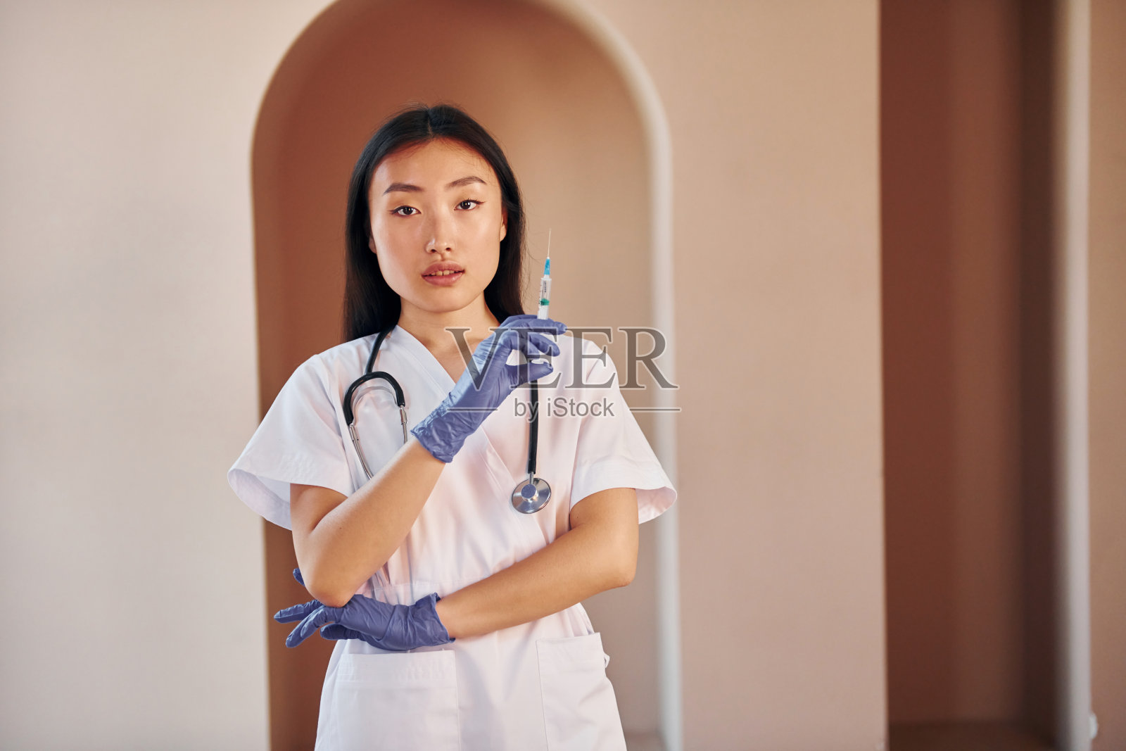 医生用注射器。年轻严肃的亚洲妇女站在室内照片摄影图片