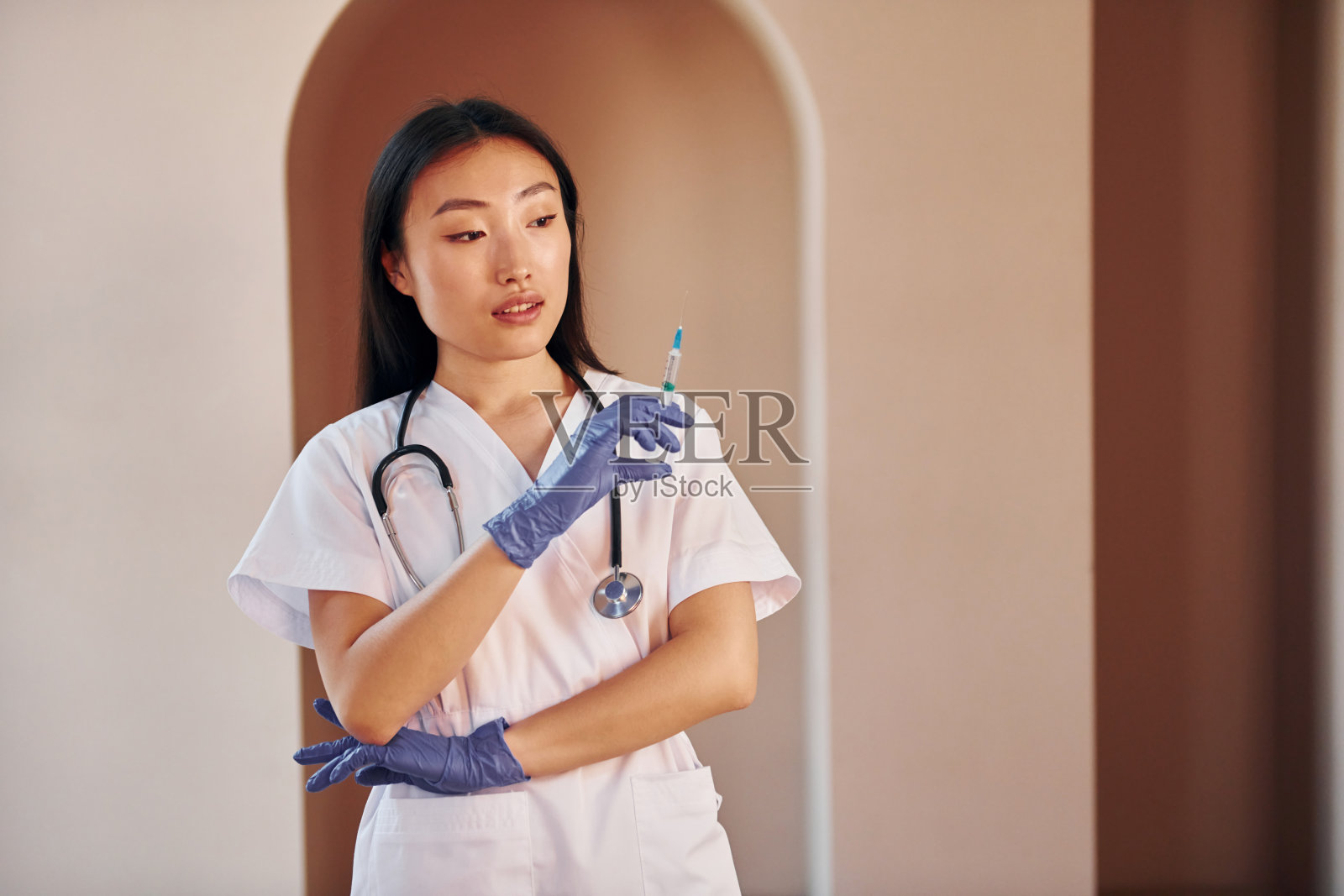 医生用注射器。年轻严肃的亚洲妇女站在室内照片摄影图片