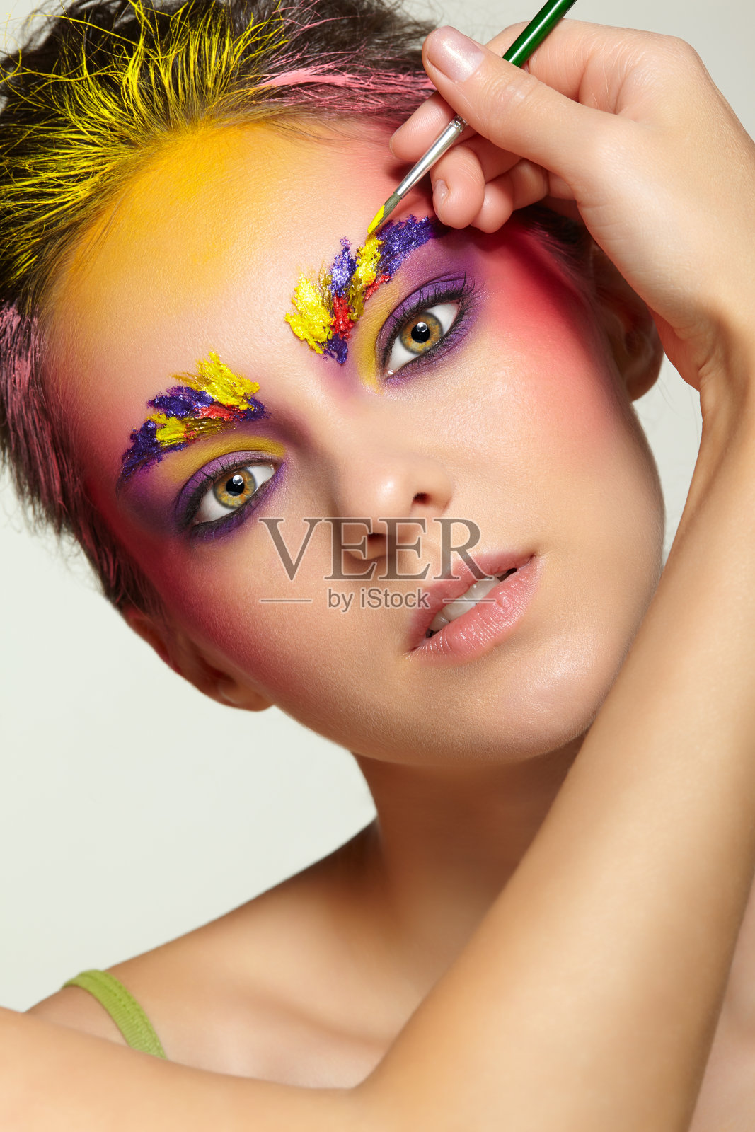 艺术家的手用画笔画出美丽女孩的眉妆。照片摄影图片