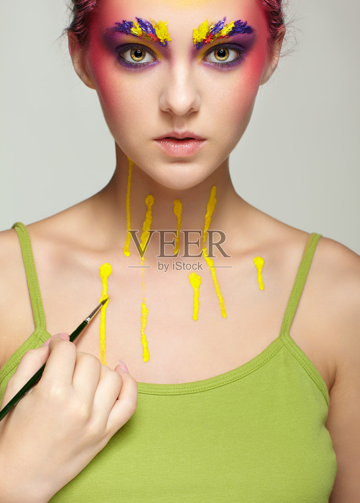 女性肖像与不寻常的脸和身体艺术化妆。女人用画笔画画。照片摄影图片