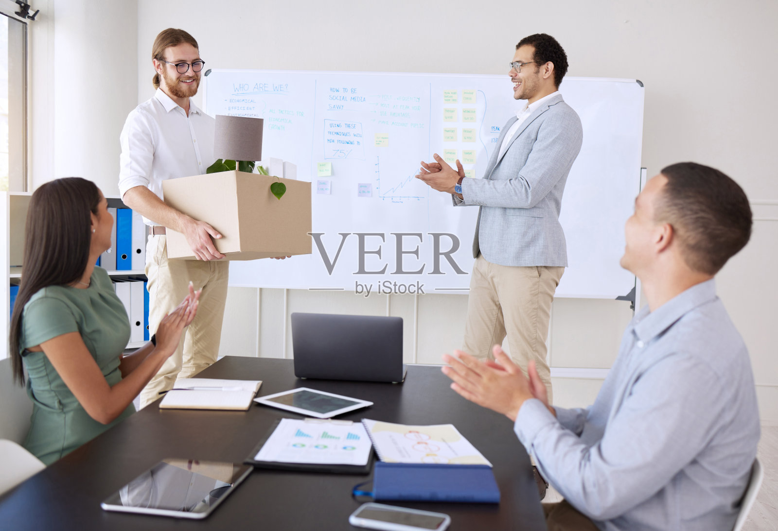 一群不同类型的商人在办公室开会时向一位同事鼓掌祝贺照片摄影图片