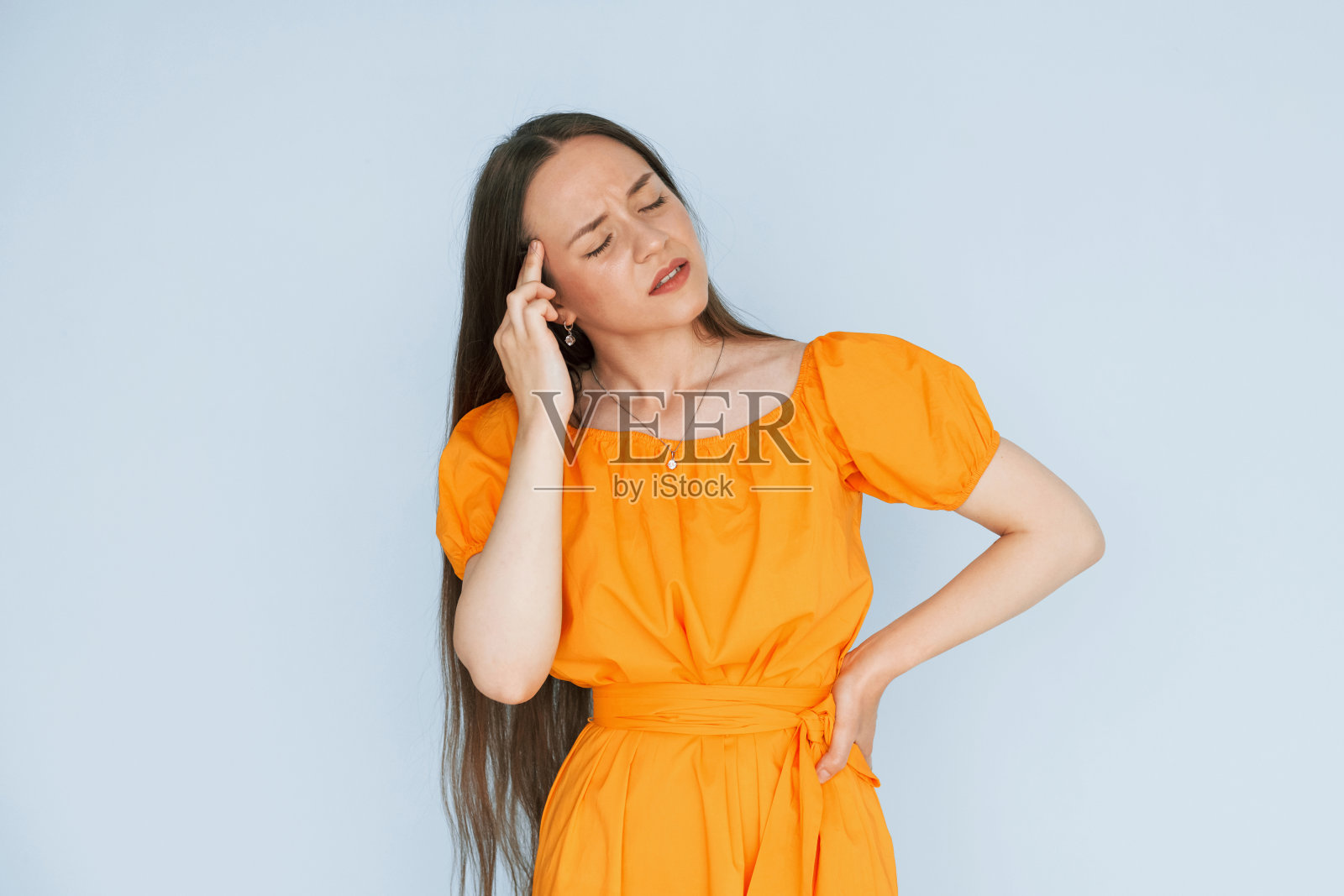 感觉疼痛。年轻女子穿着休闲服站在演播室的室内照片摄影图片