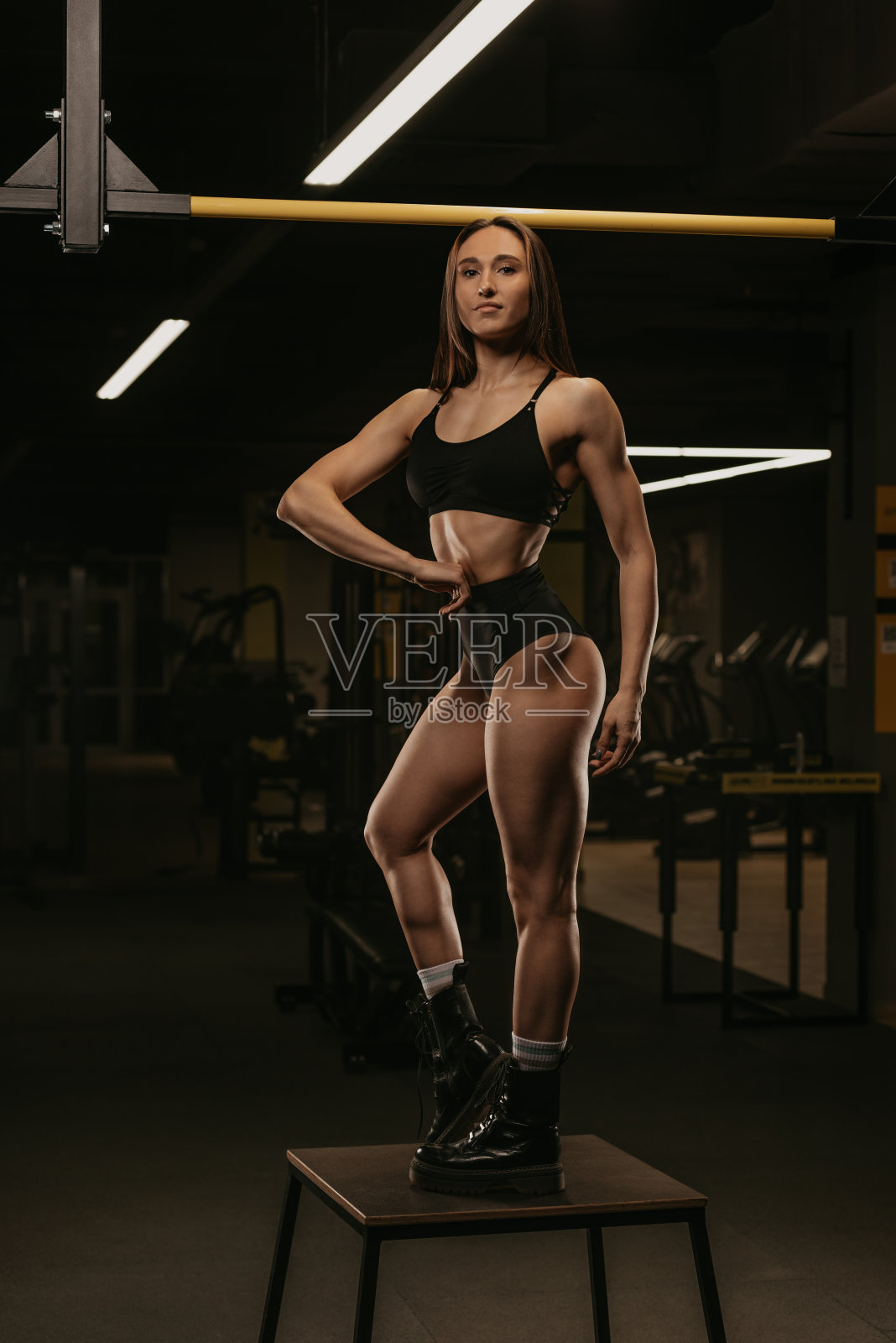 一名运动女孩在健身房里进行背部锻炼后，手放在腰上摆造型照片摄影图片