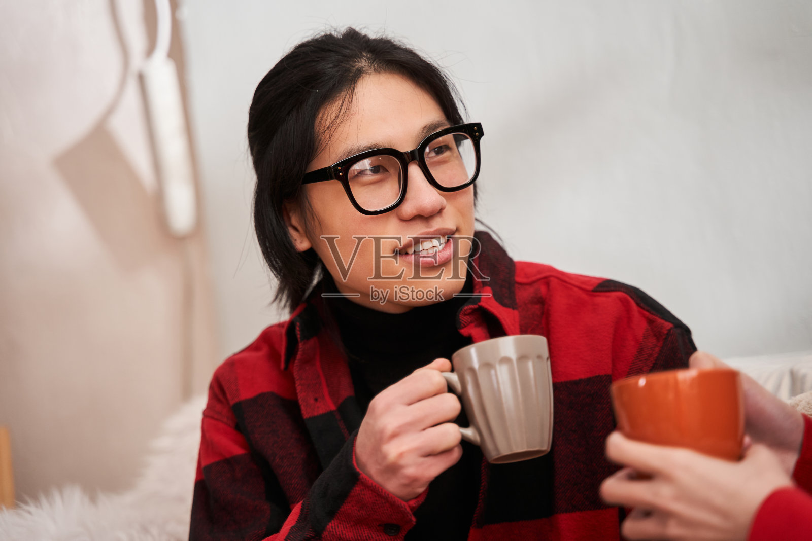 中国男子戴着眼镜，端着茶，看着他的女朋友照片摄影图片