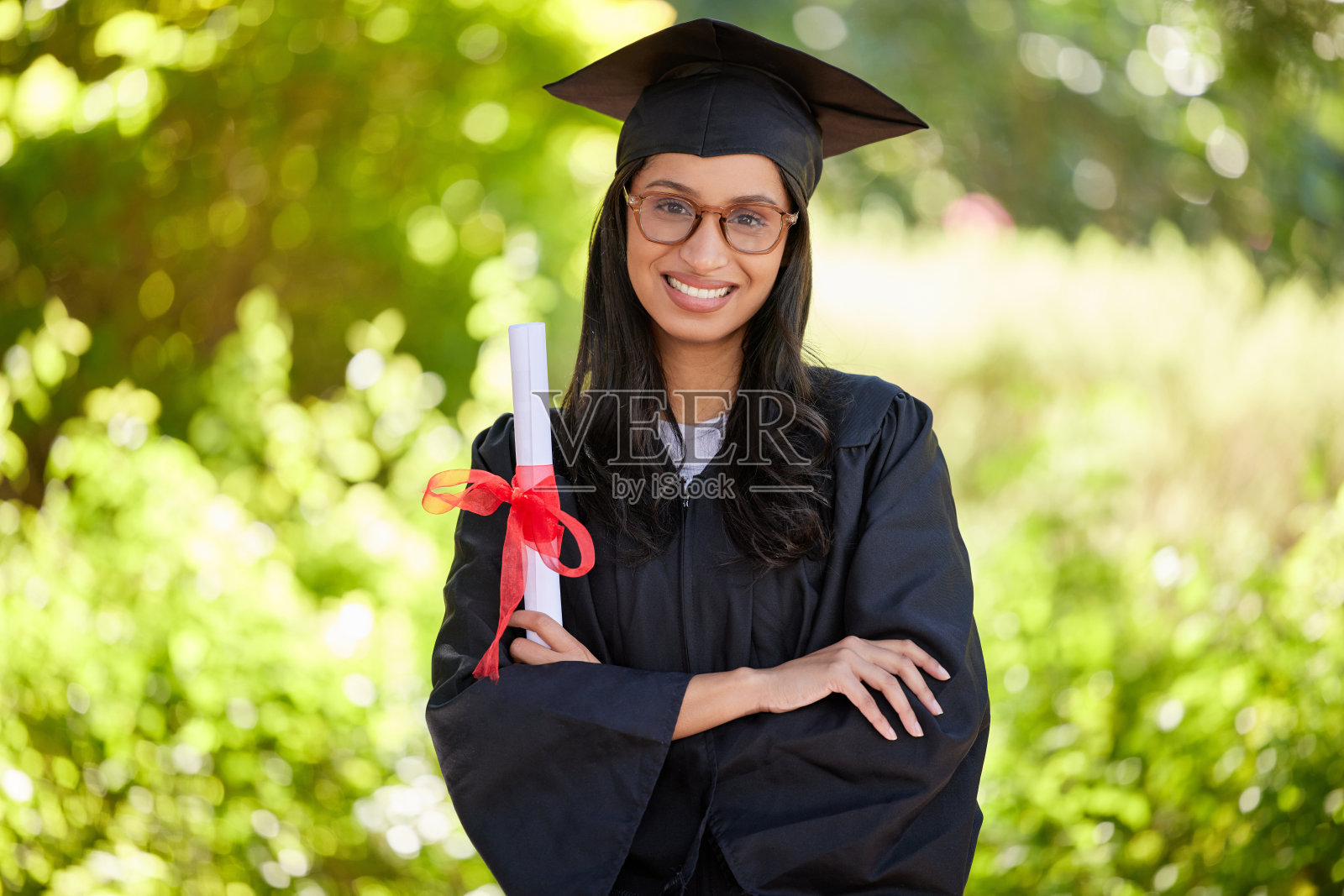 剪裁的肖像一个有吸引力的年轻女毕业生摆姿势与她的学位照片摄影图片