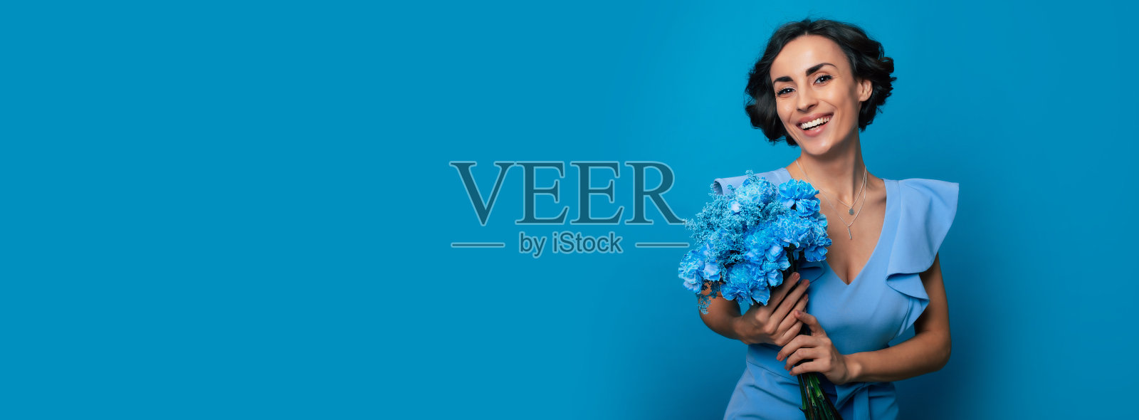 一位身穿蓝色礼服的快乐年轻女子手捧鲜花摆姿势，庆祝母亲节和妇女节，迎接春天照片摄影图片