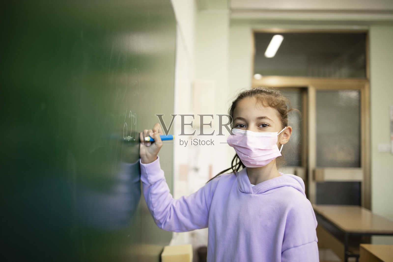 在冠状病毒大流行期间，孩子们在教室里戴着口罩。照片摄影图片