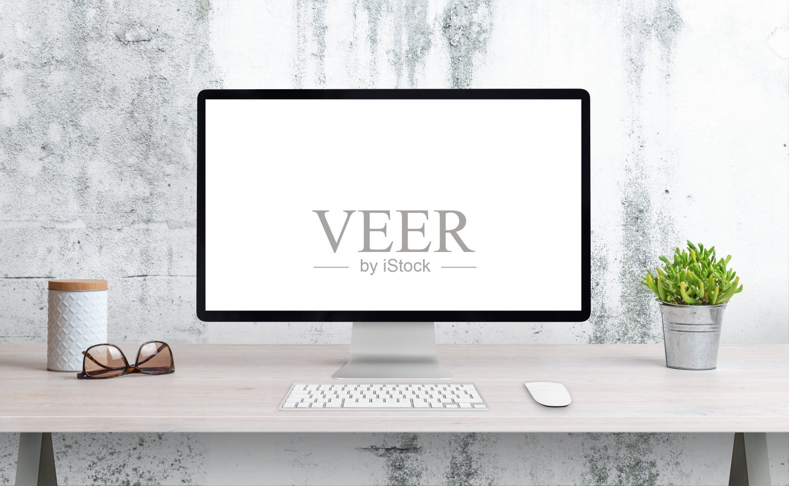 电脑显示在办公桌上与隔离屏幕的模型，wep页面演示。用植物、玻璃杯和盒子清洁办公桌。背景是白色的粗墙照片摄影图片