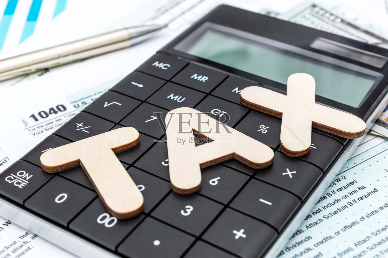 税务表格和财务文件上的单词“税”和计算器。照片摄影图片