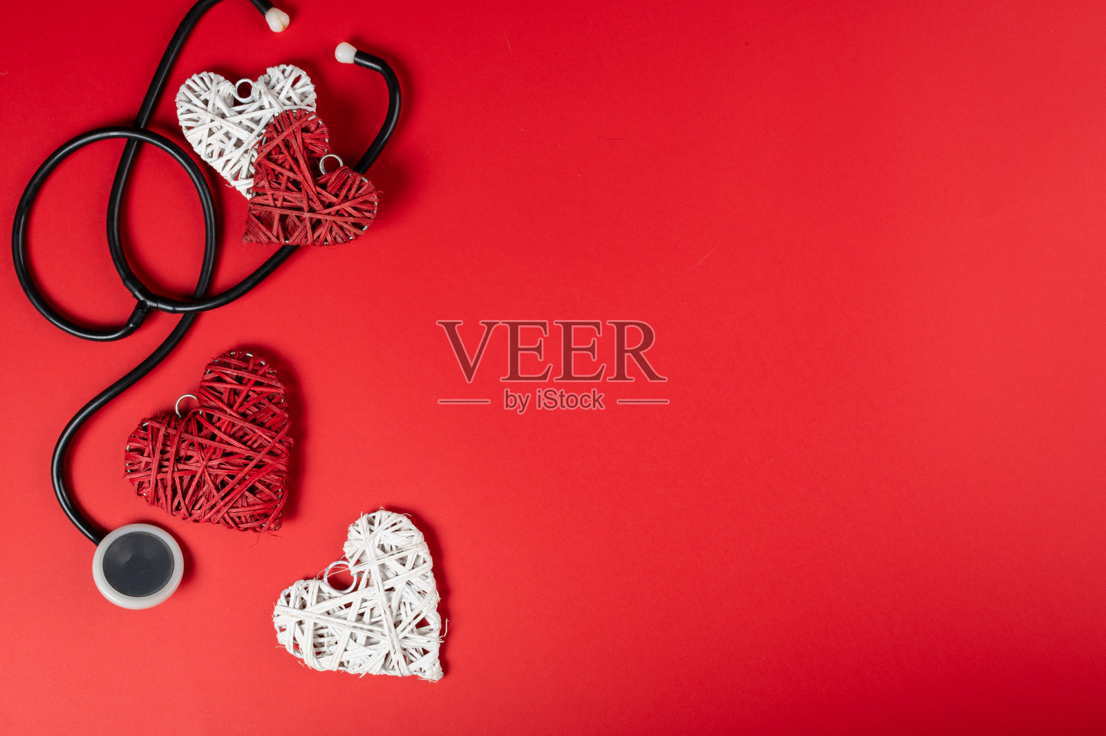 情人节和甜蜜的一天的概念。红色背景上的红心听诊器。爱情象征着健康和幸福。照片摄影图片