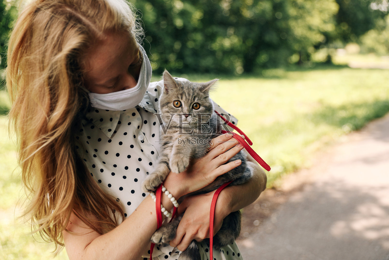 戴面具的女孩带着小猫散步照片摄影图片