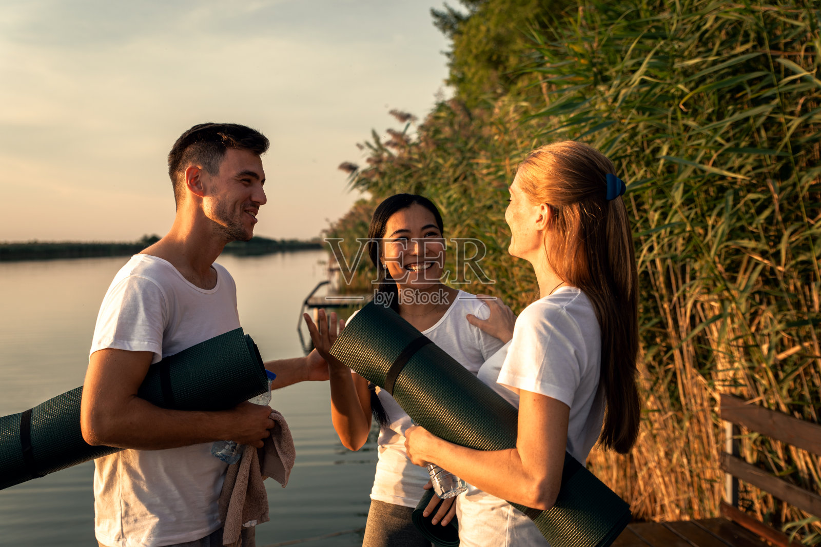 日落时分，一群人在湖边练完瑜伽后聊天。照片摄影图片
