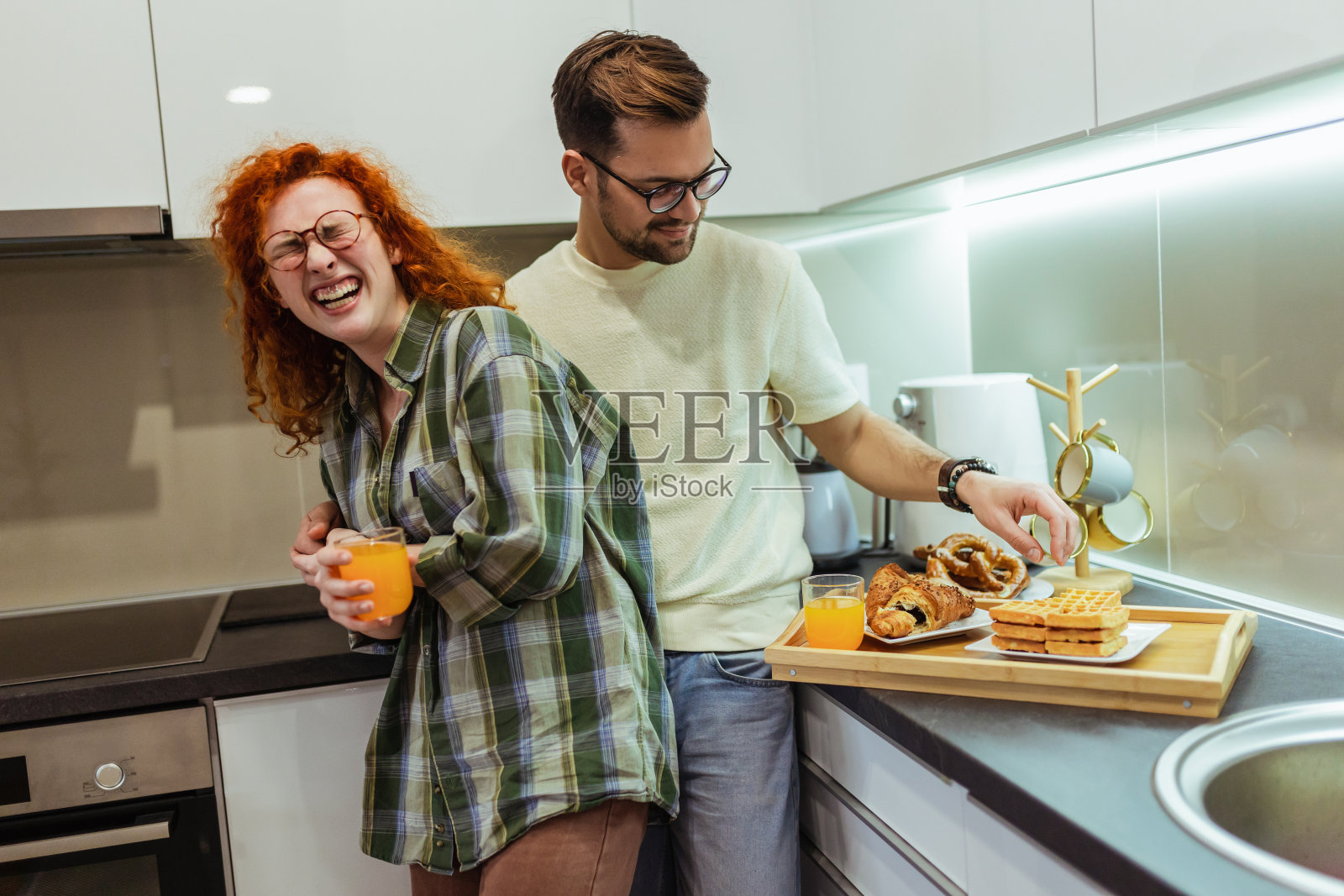 浪漫的年轻夫妇一起在厨房做饭，一起度过了美好的时光。照片摄影图片