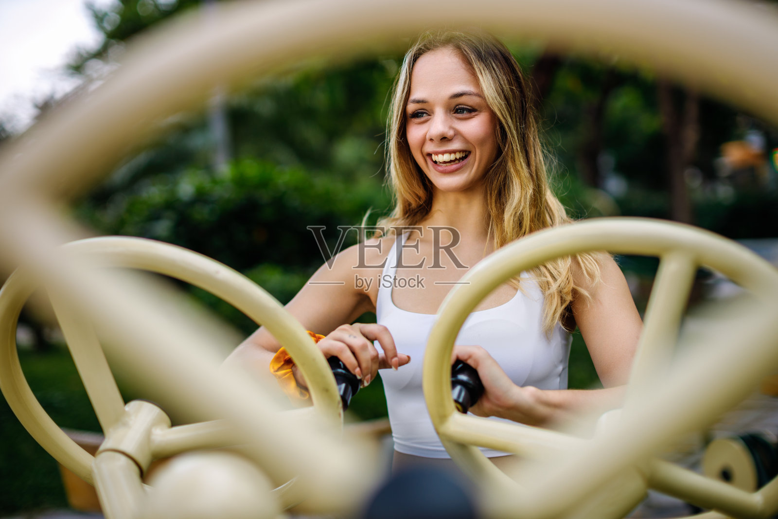 年轻女子在公园的户外健身房进行轮式旋转运动照片摄影图片