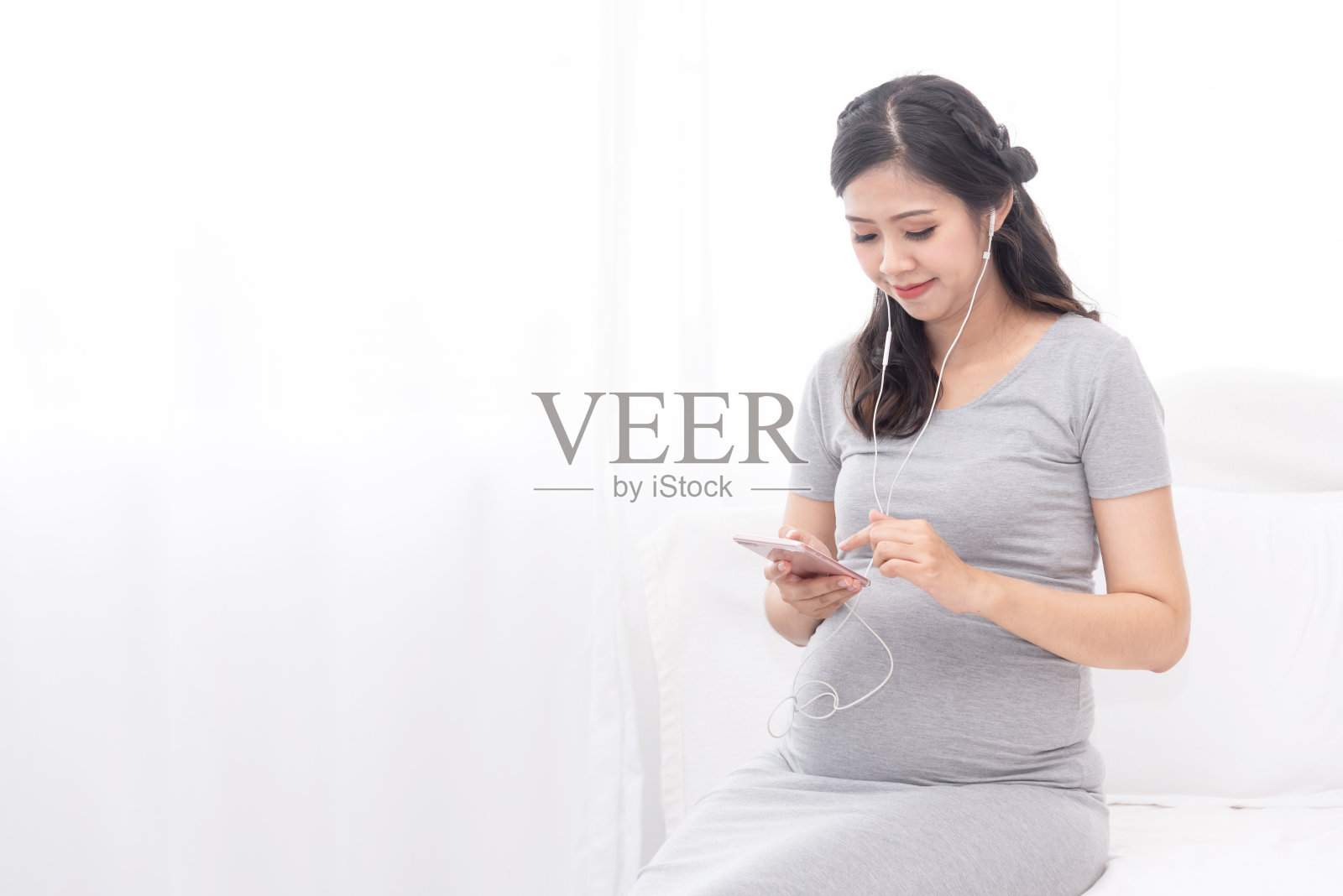 年轻美丽的亚洲孕妇听音乐和幸福的微笑照片摄影图片