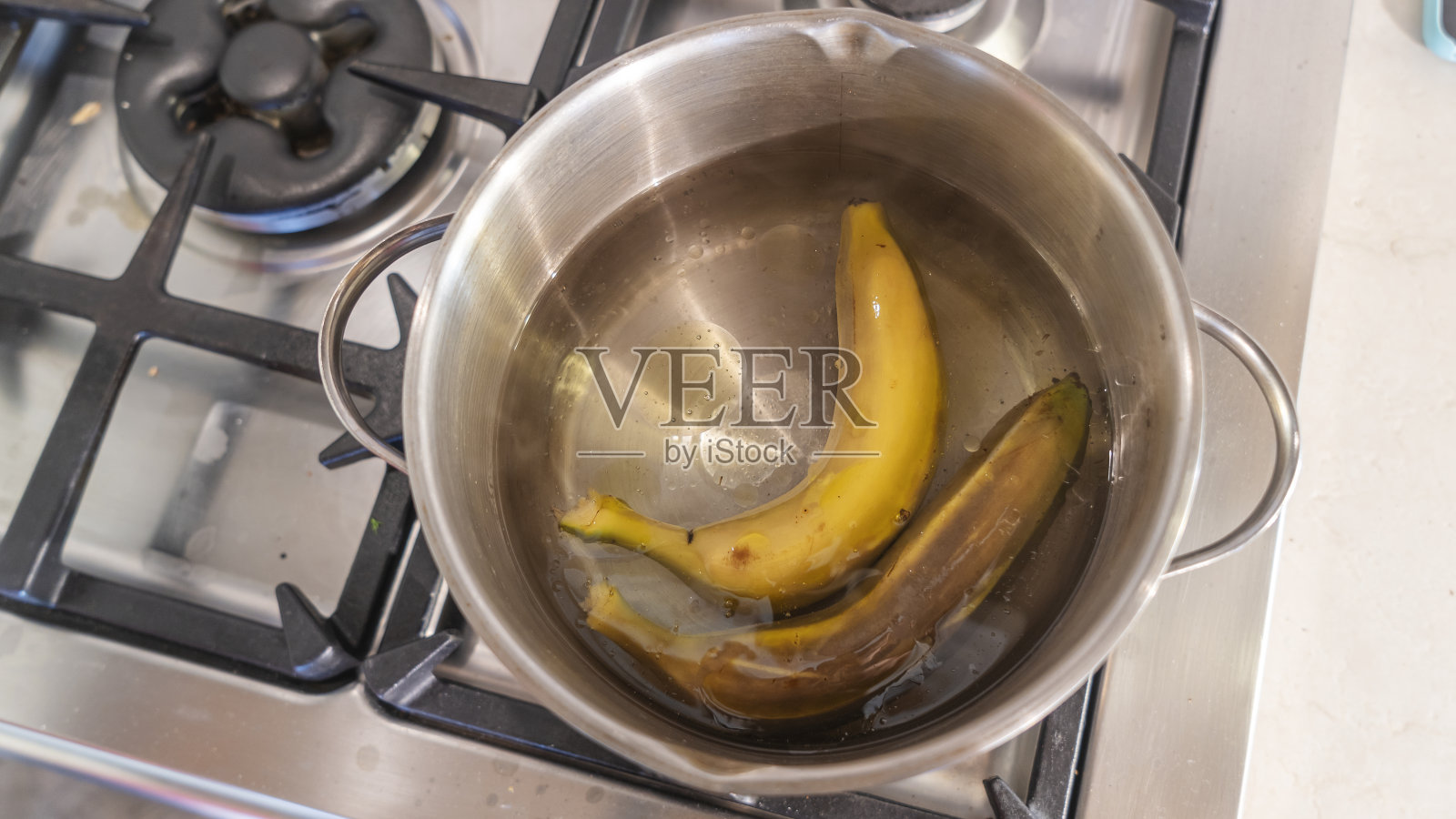 在锅里煮香蕉，高热量的零食。泰国的传统甜点。煮香蕉和香蕉叶。照片摄影图片