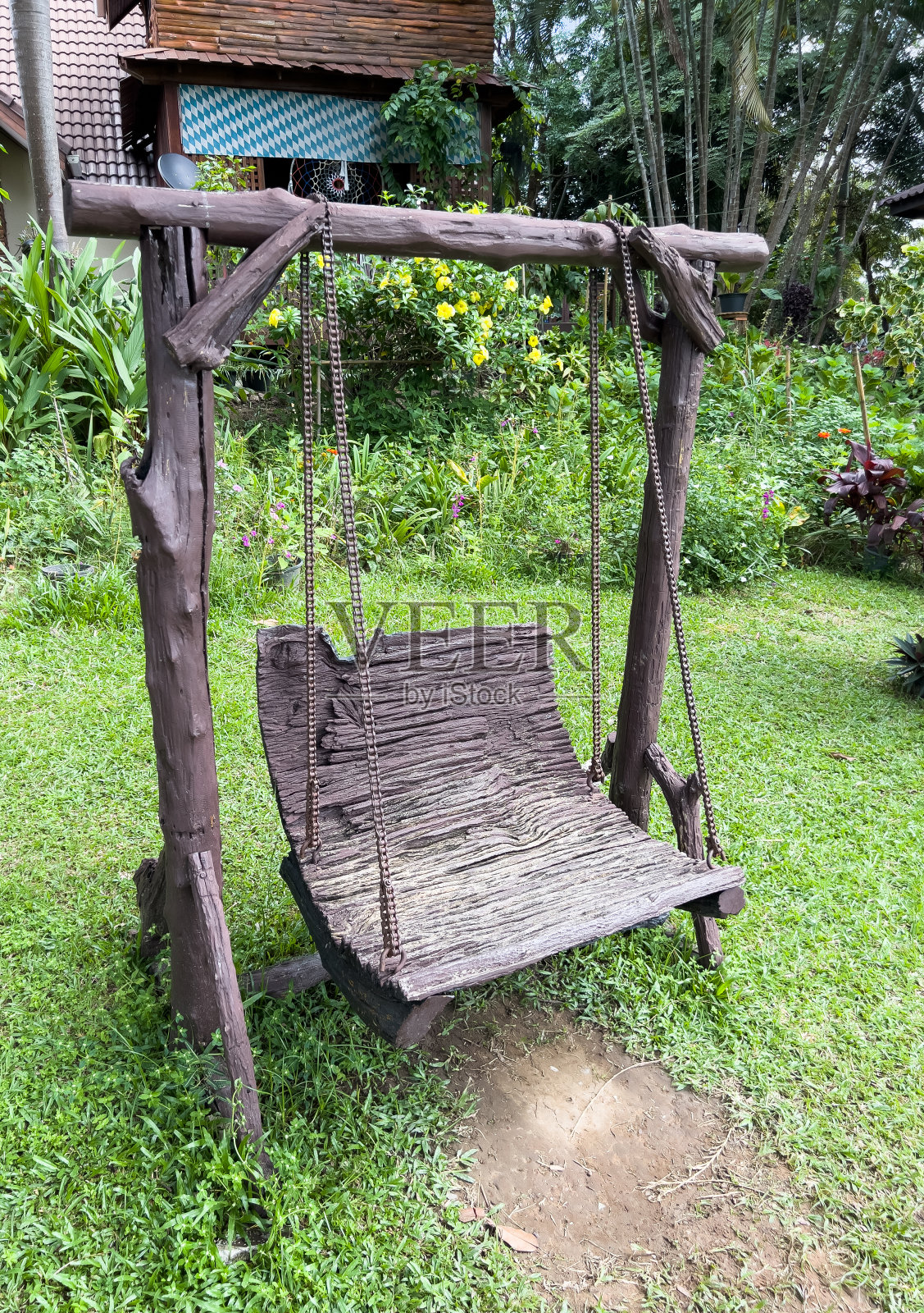 在花园里玩的带金属链条的旧木秋千。照片摄影图片