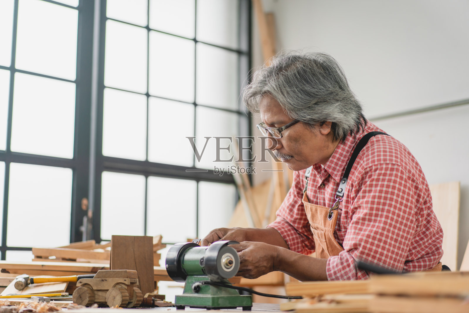 亚洲资深木匠在车间用小型磨床制作木车照片摄影图片