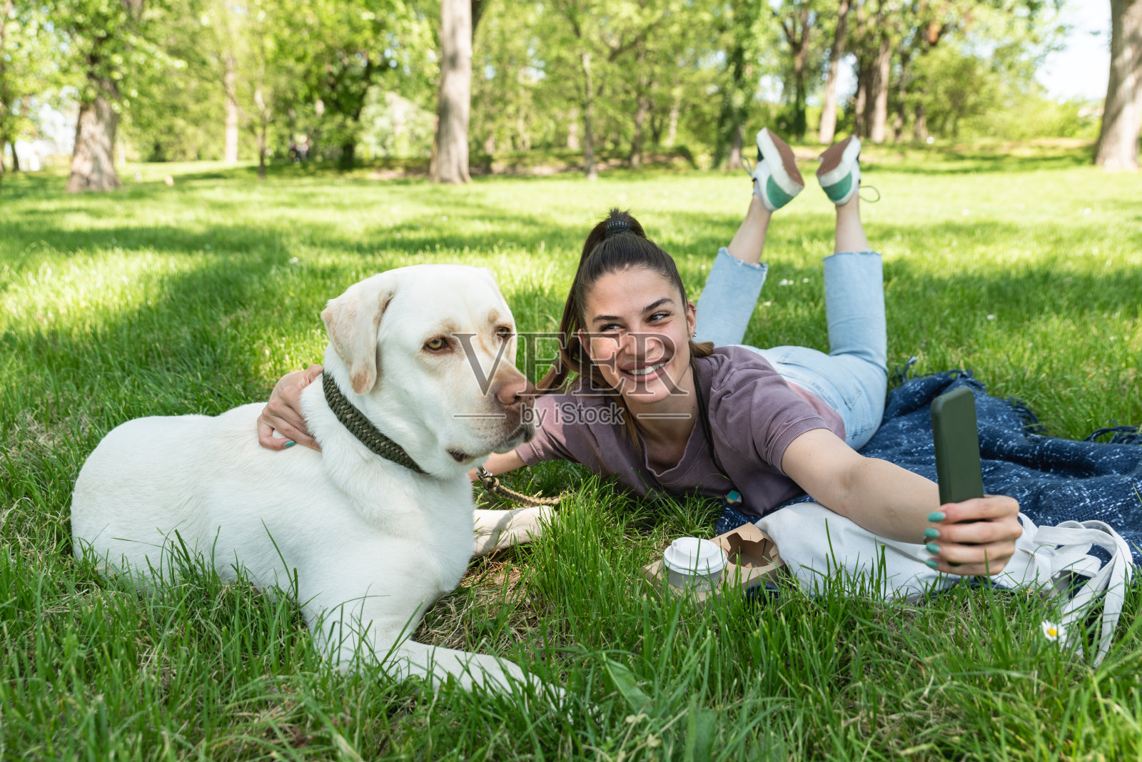 年轻的女商人在去办公室上班前带着她的宠物狗去遛狗。快乐的女主人享受自由的时间和阳光明媚的天气与她的朋友在公园里。照片摄影图片