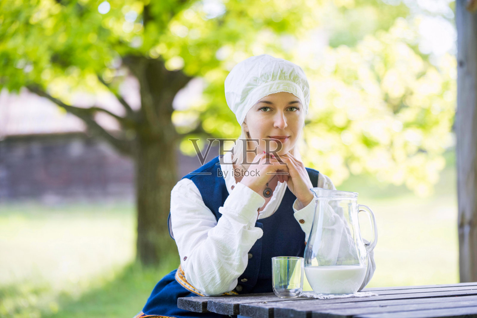 拉脱维亚妇女穿着传统服装，用牛奶玻璃装饰自然照片摄影图片