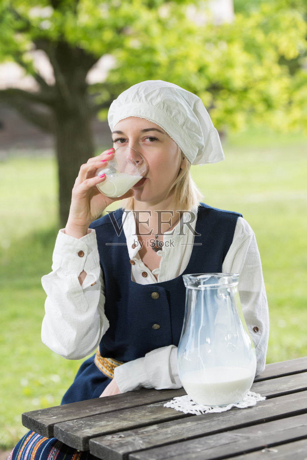 拉脱维亚妇女穿着传统服装，用牛奶玻璃装饰自然照片摄影图片