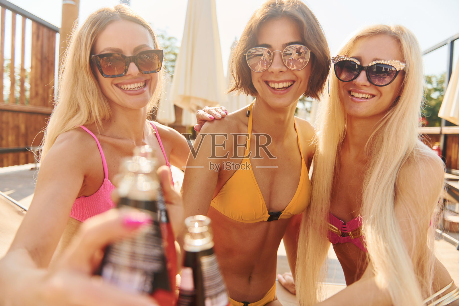 喝鸡尾酒。夏天，穿着泳装的女人在户外玩得很开心照片摄影图片