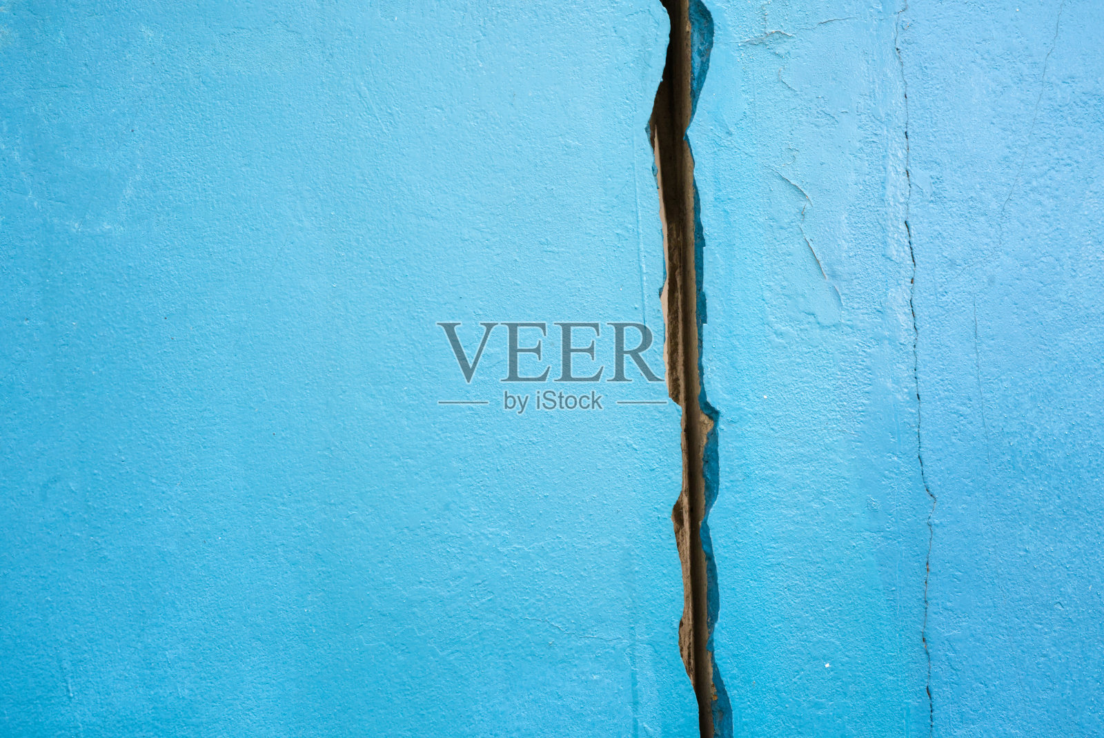自然光线下蓝色裂缝墙的纹理。照片摄影图片