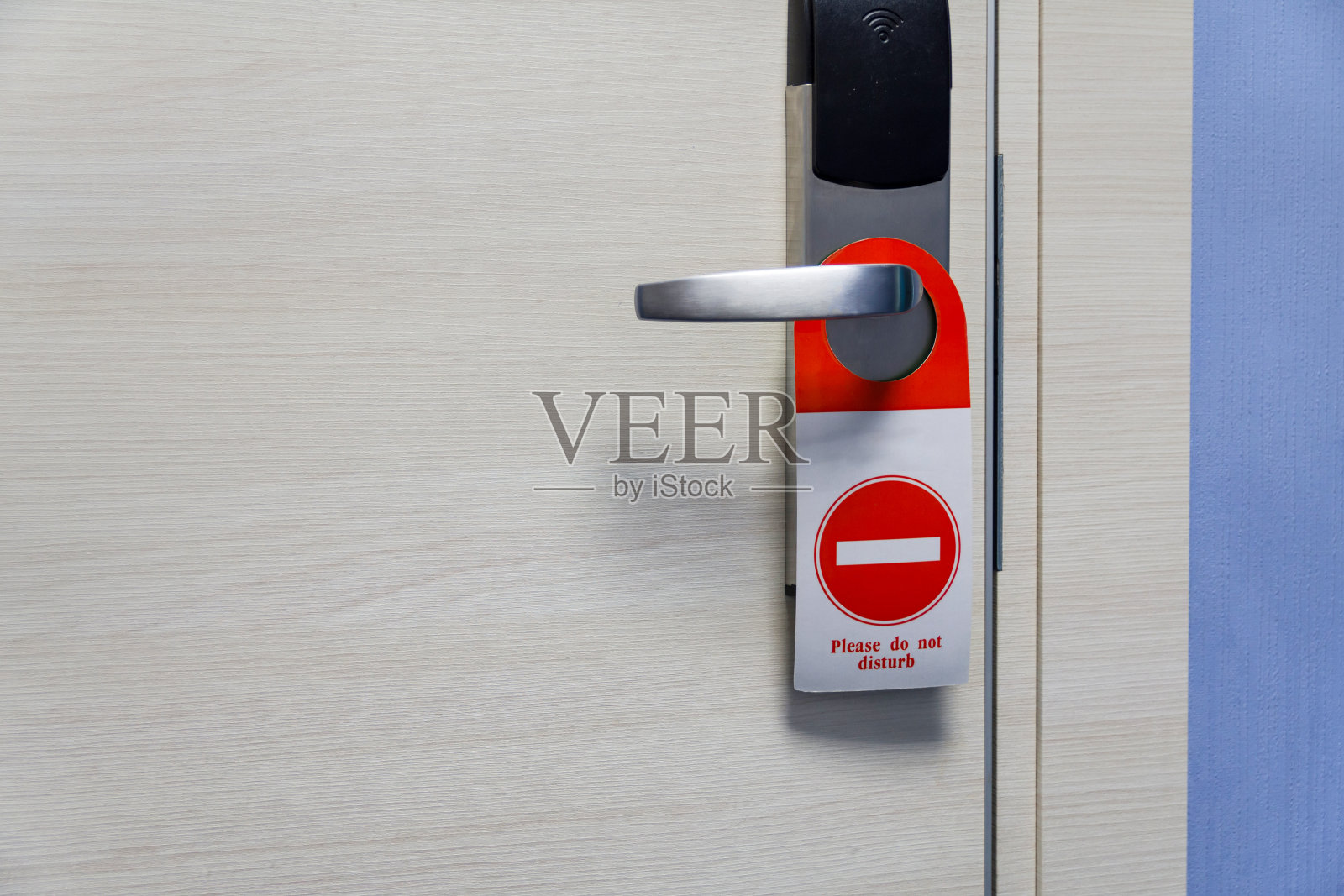 在酒店的走廊上，酒店房间的门把手上有请勿打扰的标志照片摄影图片