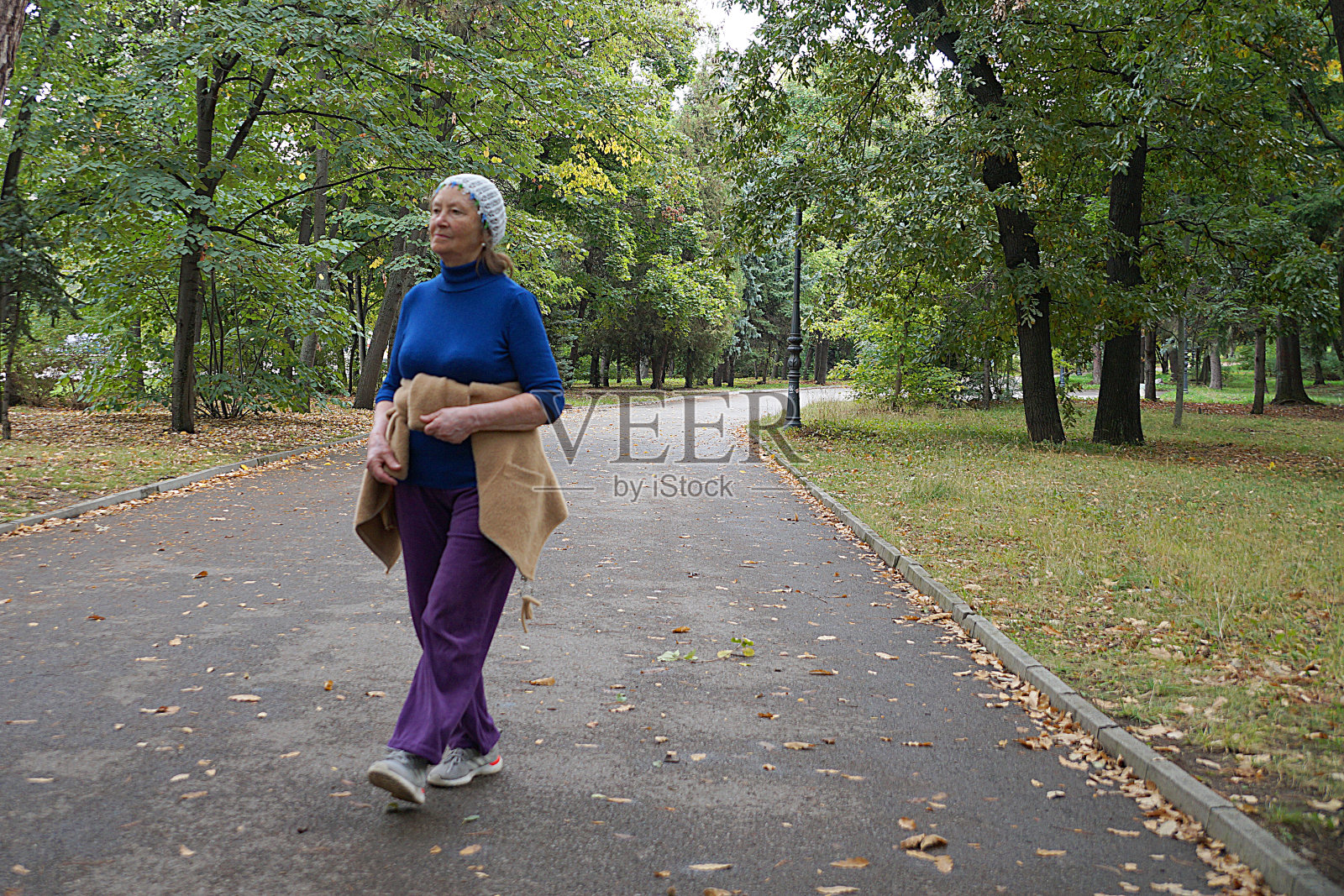 一位老年妇女独自走在秋天的公园里照片摄影图片