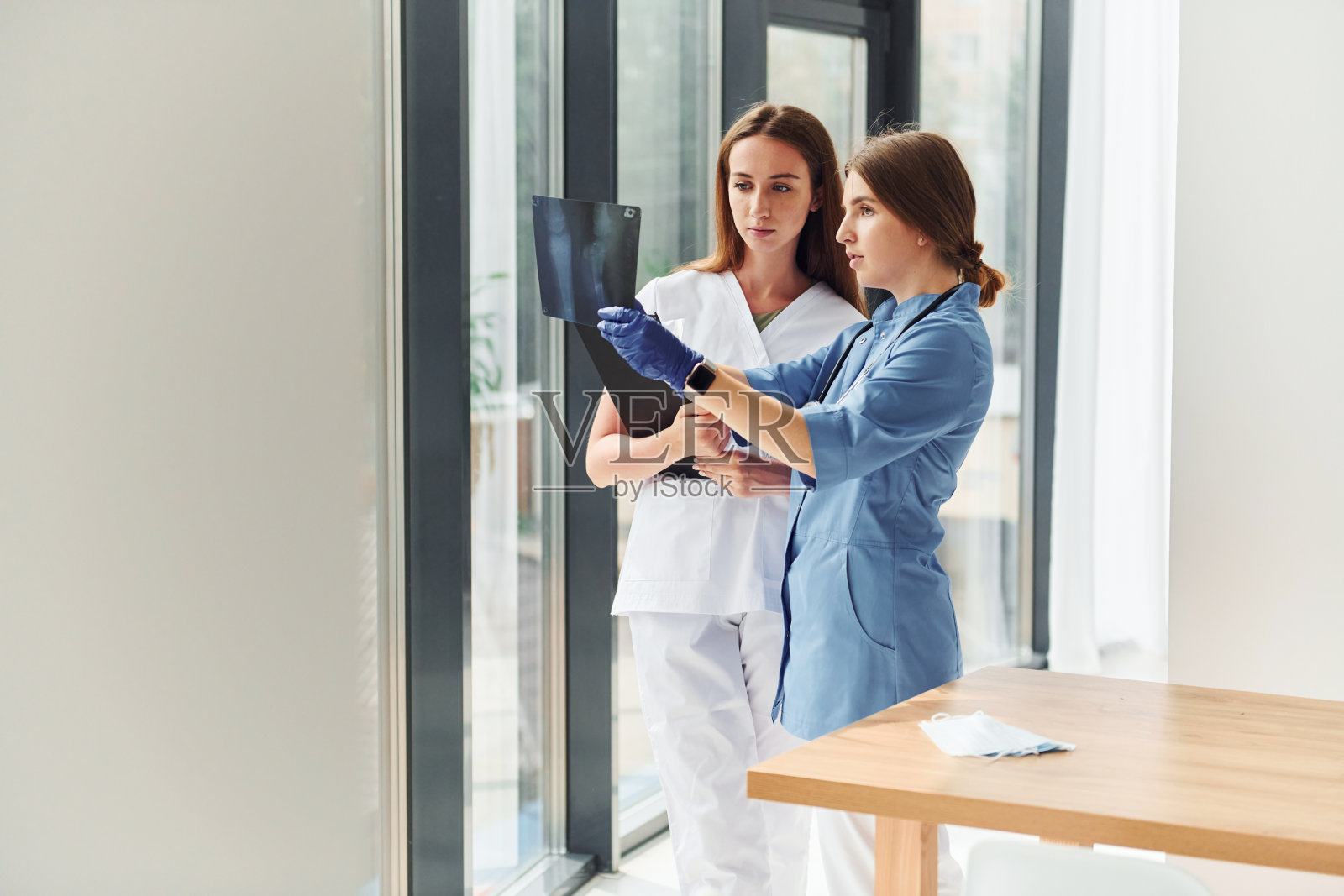 与文件。两个穿着制服的医生站在室内一起工作照片摄影图片