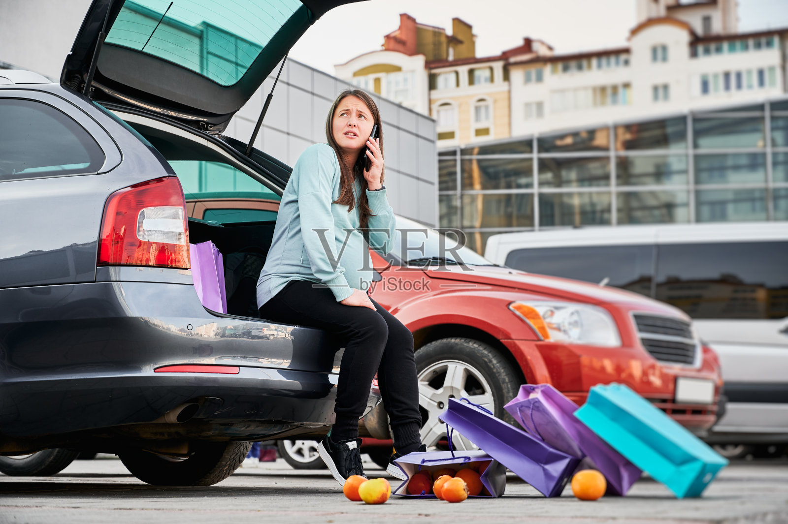 一个孕妇在停车场打电话。照片摄影图片