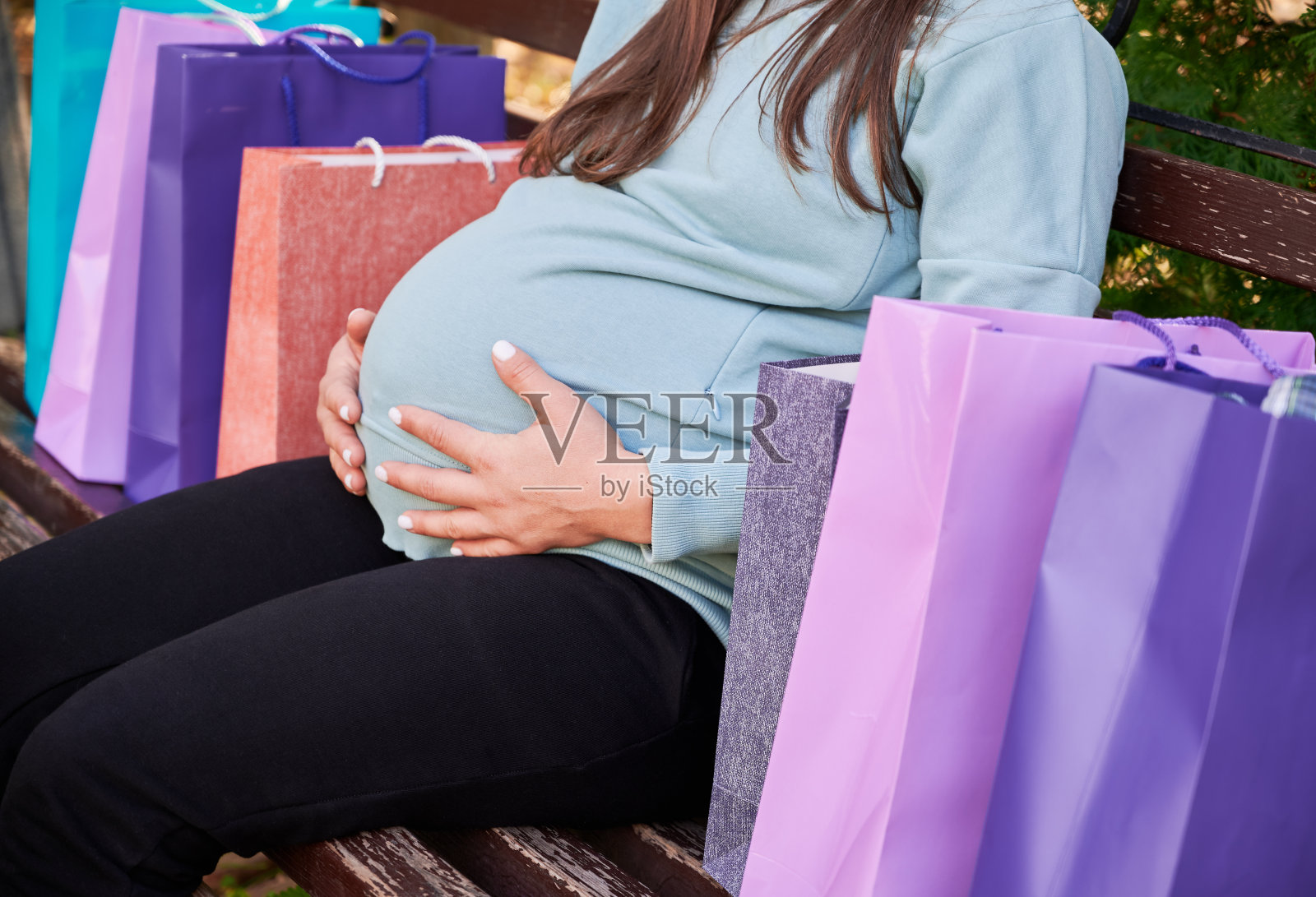 孕妇购物后在长椅上休息。照片摄影图片