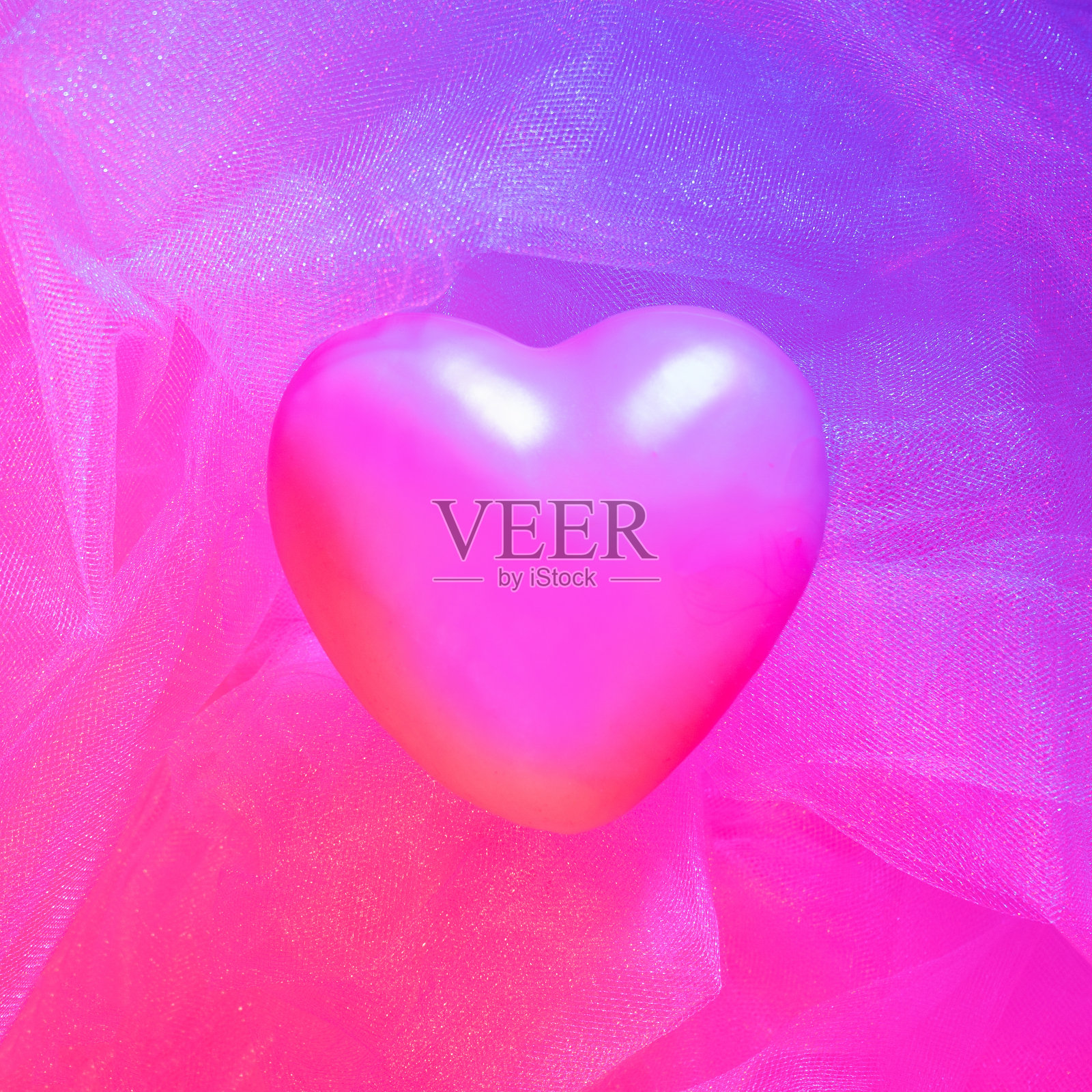 柔软的粉色心在浅粉色薄纱织物上被两种颜色点亮“u2013蓝色和红色灯。背景来自粉红色皱巴巴的薄纱。背景来自粉红色皱巴巴的薄纱。照片摄影图片