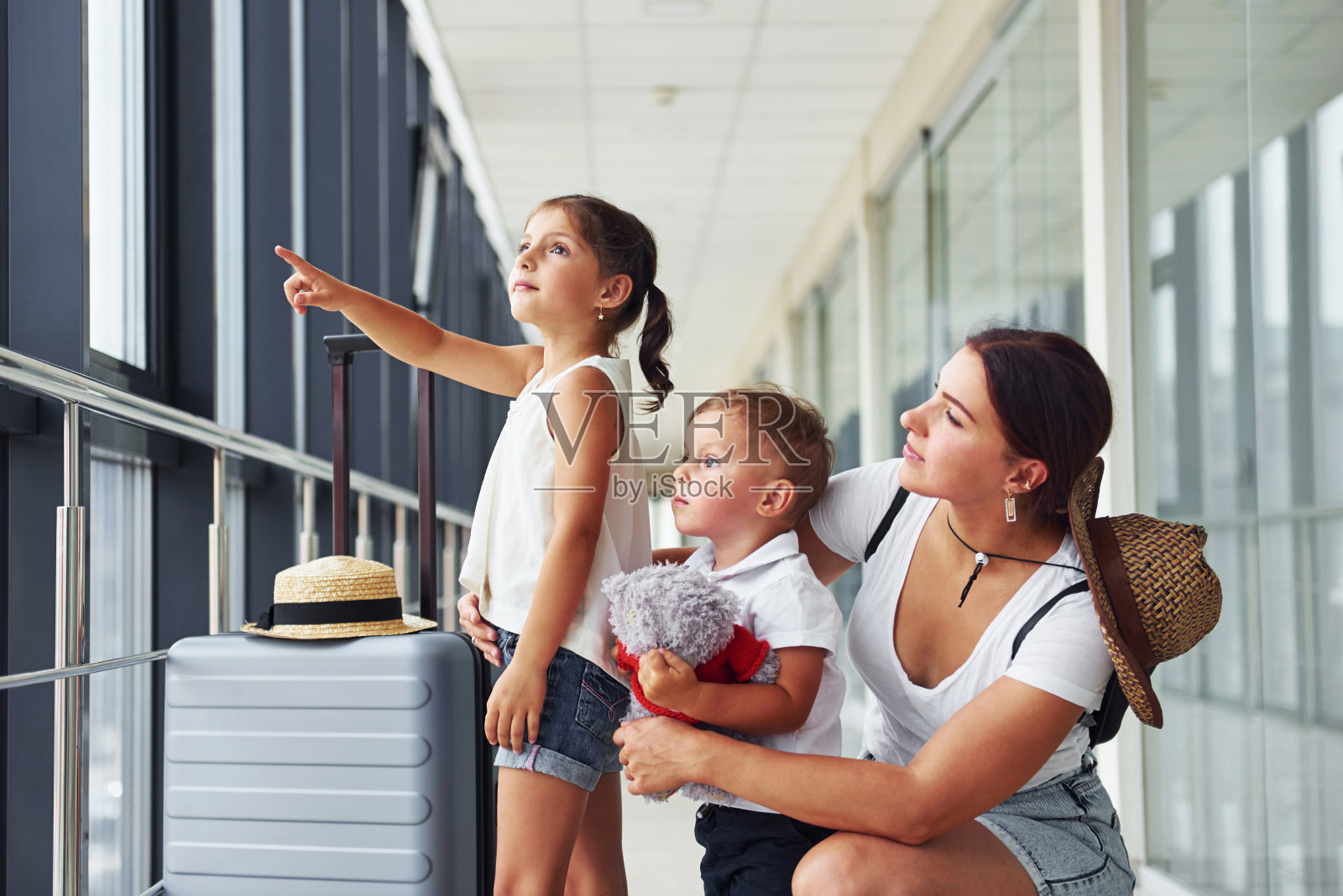 母亲带着女儿和儿子。年轻的旅客在机场的门厅里照片摄影图片